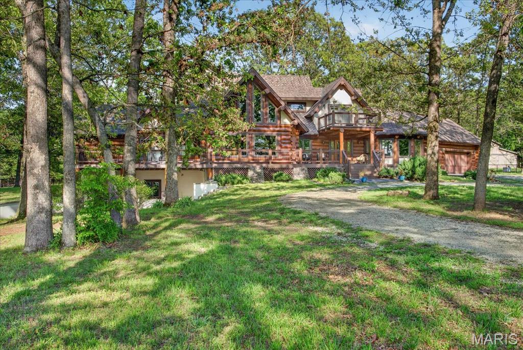 Step into a one-of-a-kind retreat that captures the spirit of Montana living, right here in Missouri. This remarkable log home offers more than 4,000 square feet of beautifully finished space, blending rustic character with refined comfort. Tucked away at the end of a nearly mile-long private drive and surrounded by scenic farmland, the setting alone makes a lasting impression. Inside, the expansive family room is the heart of the home, featuring soaring timber ceilings, oversized windows that flood the space with natural light, and a striking two-story stone fireplace that showcases exceptional craftsmanship. Above, a lofted recreation area with its own living space and en suite bath overlooks the main level, creating a perfect balance of openness and privacy. The main floor includes a spacious primary suite designed for relaxation, complete with a spa-inspired bathroom. Downstairs, the finished walkout basement expands your entertaining options with a custom bunk room and a distinctive saloon-style gathering space—ideal for hosting after a day outdoors. Throughout the home, authentic log construction shines with exposed beams, rich wood textures, and impressive structural details. The surrounding 30-acre property is equally captivating, offering wooded trails, open pasture, and thoughtfully designed spaces for horses to roam and graze. Multiple covered porches provide peaceful spots to unwind and take in the changing seasons, while the exterior amenities include a three-car attached garage and a 36x36 barn equipped with stalls and a tack room. This property offers a rare combination of privacy, craftsmanship, and natural beauty. More than just a home, it’s a lifestyle waiting to be experienced.