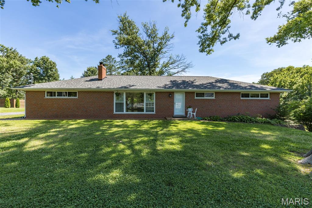 Beautiful all-brick ranch situated on a picturesque **2-acre lot complete with a pond** and a stunning backyard setting! Enjoy outdoor living on the spacious deck overlooking the park-like grounds and peaceful water views. Inside, you'll find a gorgeous kitchen featuring 42" cabinetry, quartzite countertops, stainless steel appliances, a farmhouse sink, recessed lighting, a large center island, and abundant workspace. The inviting living room showcases beautiful hand-scraped flooring, a stunning Missouri limestone fireplace with a reclaimed timber mantel, and custom built-ins that create the perfect focal point. The amazing primary bedroom suite offers a beautifully updated bath and generous closet space. Main floor laundry adds everyday convenience. Extra-wide stairs lead to the finished walkout lower level featuring a large bedroom, family room, half bath, ample storage space, and a flexible area ideal for a home office, hobby room, or workout space. An oversized garage provides additional storage and functionality. Nestled on a breathtaking **2-acre setting with a private pond**, this exceptional property combines quality craftsmanship, comfort, and timeless character both inside and out, offering the perfect blend of privacy, natural beauty, and everyday living.