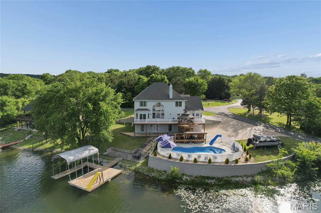 Just in time for summer entertaining! Experience true resort-style living in this remarkable 4-bedroom, 4.5-bath, one-and-a-half-story lakefront residence offering over 4,200 square feet of thoughtfully designed living space. Perfectly situated on two beautifully landscaped lots within a gated community, this home delivers luxury, privacy, and unforgettable views of Summer Set Lake. 

Abundant natural light fills the home, highlighted by a stunning Palladian-style window in the great room, soaring 18-foot ceilings, and a dramatic stone front wood-burning fireplace. The open floor plan creates seamless flow for both everyday living and entertaining. Just off the kitchen, a cozy breakfast nook provides serene lake views, while the kitchen itself offers generous storage, beautifully crafted cabinetry, and ample counter space—ideal for preparing meals or hosting holiday gatherings in the formal dining area. 

The expansive primary suite on the main level is a true retreat, featuring rich hardwood flooring, elegant coffered ceilings, and direct access to the deck overlooking the lake—perfect for enjoying peaceful evenings by moonlight. The recently remodeled en suite bathroom is exceptionally appointed with a mounted television, corner jacuzzi tub, walk-in shower, and a double-bowl vanity with oversized tile. A charming bay window frames breathtaking lake views that make this space truly one of a kind. 

A second primary bedroom option is located on the upper level and includes a private full bath with tub/shower combination, along with an expansive walk-in closet offering abundant upper and lower shelving. Also on the upper level are the third and fourth generously sized bedrooms, filled with natural light and connected by a full bathroom. The rear bedroom features stunning lake views. 

The finished lower level takes entertainment to the next level. It features two bar areas, with stools included. One bar is equipped with matching Galanz refrigerator and microwave, while the second showcases beautiful copper countertops, a kegerator, ice maker, and dishwasher. Between the bar areas is an impressive 8-seat theater with power-reclining seating, a 100-inch screen, and a Bose sound system. After movie night, enjoy the adjoining billiard room for a friendly game of pool. Music enthusiasts will be especially impressed by the soundproof recording studio, complete with CAT 6 wiring and XLR, making movie nights and game days truly unforgettable. 

Outdoor living spaces are equally exceptional. A custom gazebo integrated into the deck overlooks the tranquil lake, while the backyard oasis features a newer 34' x 13' irregular in-ground heated and cooled pool, complete with chaise lounge chairs and umbrellas, as well as a brand-new 2025 Dr. Wellness 8-person hot tub. Additional outdoor amenities include designated cooking areas, a built-in stone fire pit, and expansive decking designed for gathering with friends or relaxing by the water. 

Lake enthusiasts will love the private 25' x 22' boat dock, featuring a single boat slip and a slide directly into the lake, offering endless waterfront enjoyment right in your own backyard. 

Additional highlights include EV hookup in the lower level, copper plumbing, upgraded exterior doors with thumbprint entry, a new roof installed Summer 2025, and a dual HVAC system that is just one year old. Many personal property items are also included. 

This one-of-a-kind lakefront home seamlessly blends elegance, recreation, and luxury—offering a rare opportunity to own a premier property designed for making memories year-round. This exceptional home will not last long.