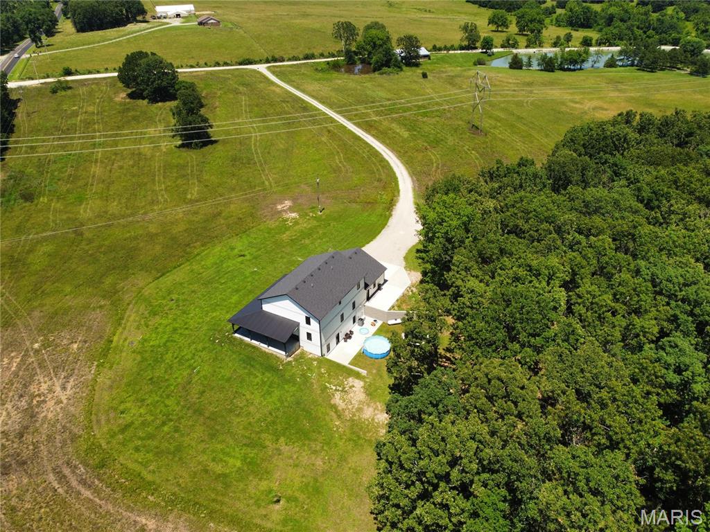 Welcome to an exceptional property where space, style, and functionality come together on 16 picturesque acres. Built just two years ago, this custom-designed home offers 7 bedrooms, 4 full bathrooms, 3 separate living areas, dual laundry rooms, an oversized side-entry garage, and additional concrete parking, creating the balance of everyday convenience and entertaining. The thoughtfully designed main level features an open-concept floor plan centered around a spacious kitchen complete with solid surface countertops, a tiled backsplash, pot filler, walk-in pantry, and a large center island with seating. The primary suite is privately situated at the rear of the home, offering peaceful wooded views, a luxurious bath, and a custom walk-in closet. Also located on the main level are a second bedroom, a dedicated office with a window and closet, an additional full bath, and a conveniently located laundry room just off the garage with custom mudroom storage. An impressive cable-railed staircase leads to the upper level, where expansive windows overlook the main living area below and fill the home with natural light. This level features an open family room, three generously sized bedrooms, a full bathroom, and a second laundry area, providing comfortable living space and added convenience for family and guests. The finished lower level was designed with fun and family in mind, featuring an oversized third living space with durable concrete floors, a large seventh bedroom, a full bathroom, central vacuum system, Culligan water system, and ample storage. Outside, the home makes a lasting impression with its bold architectural design, stone accents, vertical siding, and wraparound covered porch. As you travel down the long private drive, you'll pass a pond before arriving at this one-of-a-kind masterpiece. Conveniently located with easy access to Fort Leonard Wood and Interstate 44, this property delivers the perfect combination of rural living and everyday accessibility. This is country living at its finest. Rarely does a home combine acreage, modern construction, thoughtful design, tranquility of country living, and stunning curb appeal in such a remarkable package. This is country living at its finest.