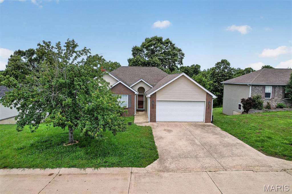 Welcome to 215 Settlers Pass, located in the Waynesville School District and just a short drive to the West Gate of Fort Leonard Wood. This spacious 4-bedroom, 3-bathroom home offers a functional layout with room to spread out both inside and out. The main level features an open-concept living, dining, and kitchen area designed for everyday living and entertaining. A breakfast bar overlooks the living room, creating a seamless flow throughout the heart of the home. The owner's suite offers a private retreat complete with a soaker tub, separate stand-up shower, and dual vanity. Two additional bedrooms and a full bathroom are also located on the main floor. Downstairs, you'll find an impressive finished basement offering a substantial amount of additional living space, including an oversized fourth bedroom, third full bathroom, laundry room, and a large family room with plenty of space for a designated play area.. Step outside onto the rear wood deck and enjoy the peaceful wooded views just beyond the large back yard, that provide a beautiful natural backdrop and added privacy. Recent updates include the roof, interior paint, carpet, and bathroom improvements. A two-car garage and spacious backyard complete this move-in-ready home.