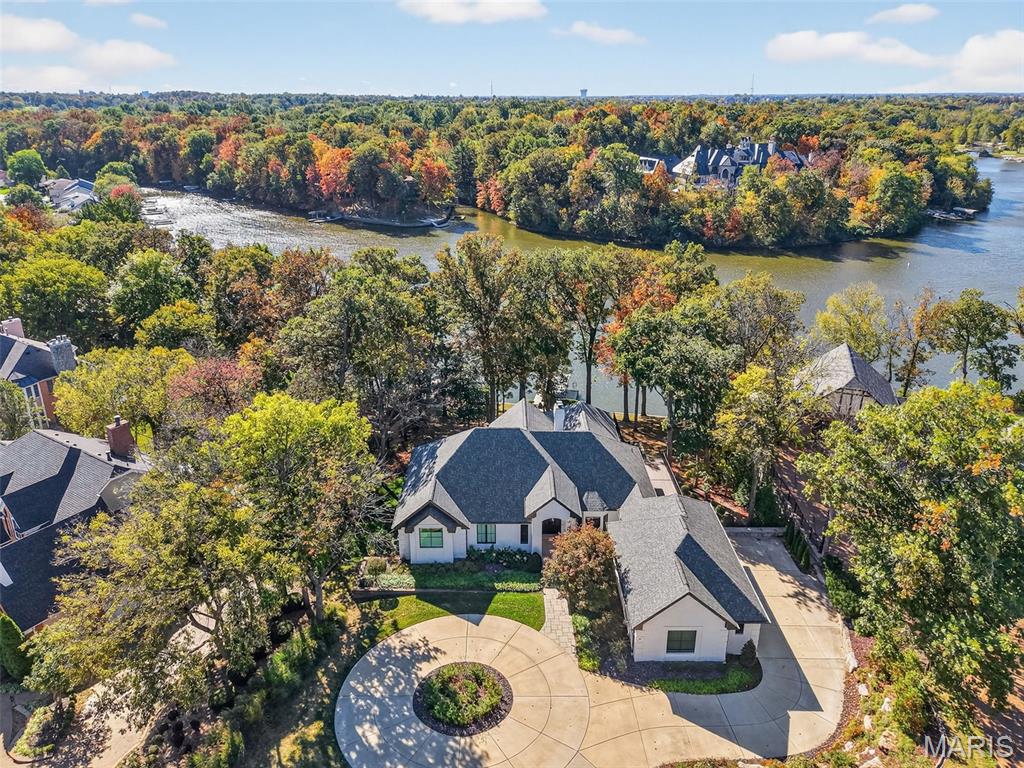 Stunning fully remodeled waterfront ranch in Lake St. Louis, perfectly positioned on a deep-water no-wake cove with a newer covered private dock and lift. Rebuilt down to the studs with uncompromising quality and professionally curated finishes throughout, this fully turnkey home offers more than 6,000 square feet of thoughtfully designed living space on a picturesque .76-acre lot with panoramic lake views from nearly every room. The striking exterior showcases a circle drive, paver walkway and patio, professional landscaping and lighting, whitewashed brick, James Hardie siding, Pella windows and doors, and a grand arched entry. Inside, expansive rear-facing windows frame the water and fill the home with natural light. A warm modern aesthetic of layered whites, blacks, and natural tones creates an inviting yet sophisticated atmosphere. The vaulted living room offers dramatic scale anchored by a fireplace and stunning lake views. Designed for entertaining, the chef’s kitchen features Caesarstone countertops, an oversized island, custom floor-to-ceiling cabinetry, a Wolf gas range, built-in Sub-Zero refrigerator, drawer microwave, two dishwashers, and seamless flow into the breakfast room, dining room, great room, and sunroom. Wrapped in windows, the sunroom opens through Pella sliding doors to the composite deck, creating effortless indoor-outdoor living. The main-floor primary suite is a private retreat with lake views, tray ceiling, dual walk-in closets, and a spa-inspired bath. An office or additional bedroom, second full bath, and spacious laundry room with custom built-ins complete the main level. The walkout lower level expands the living space with a large family room featuring a gas fireplace, wet bar, and access to the paver patio with outdoor gas fireplace. A second recreation room, three additional bedrooms, two full baths, second laundry room, and four-seasons room provide exceptional flexibility for guests and everyday living. Outside, the gentle walk to the water leads to the covered dock and lift, ready for boating season. Beyond the home, Lake St. Louis offers a lifestyle centered around recreation and community with private lakes, golf courses, pickleball and tennis courts, clubhouse, pools, fitness center, parks, and the celebrated Fourth of July fireworks display residents look forward to each year. Located in sought-after Eastern Shore Estates, approximately 30 minutes from an international airport, 22 Holloway Dr offers the rare opportunity to enjoy luxury waterfront living where everyday feels like a vacation.