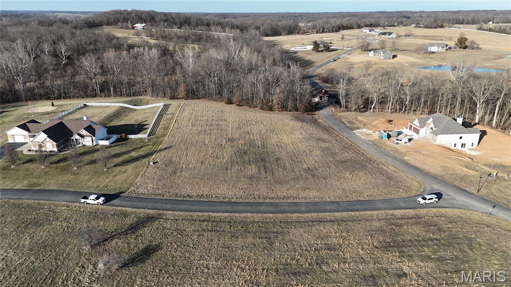This lot is suitable for building a custom home with buyer-selected plans and builder. No time limit to build. Water and electricity are available on site. The property includes protective restrictions to maintain neighborhood standards. It backs directly to mature woods and a creek, providing natural privacy and a wooded rear boundary. The lot is open with convenient access at the subdivision entrance and corner positioning for added visibility. Shouses and barndominiums are not permitted.