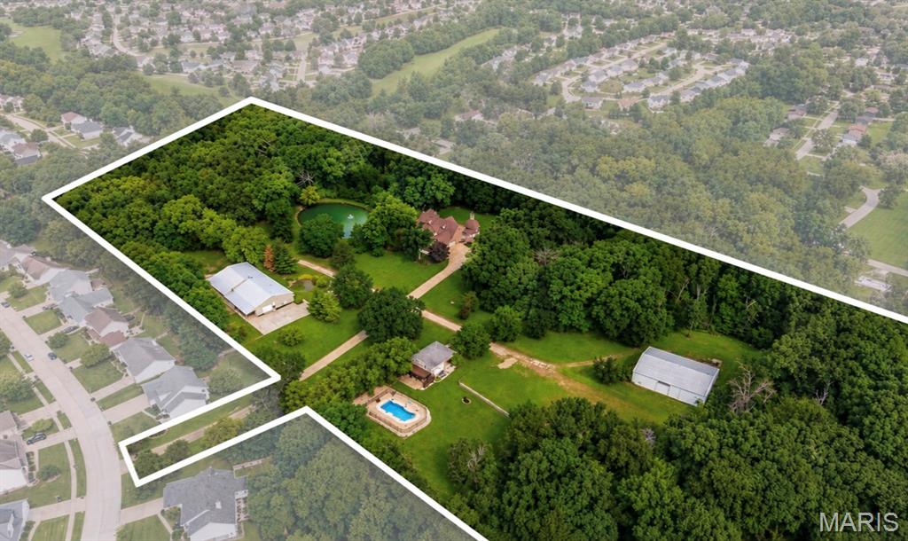 A truly one-of-a-kind 15-acre estate in the heart of O’Fallon, offering a rare combination of luxury, privacy  and versatility. The property consists of an impressive main residence, two outbuildings, a separate guest house, inground pool and pond, creating a setting unlike anything else in the area. Whether envisioned as a private family compound, multi-generational estate, or a space to operate a small business, the possibilities are endless. The all brick and stone executive atrium ranch offers nearly 8,000 sq ft of beautifully appointed living space with 5 bedrooms, 6 bathrooms and timeless architectural detail throughout. Multiple gathering spaces, custom finishes and an expansive finished lower level provide an exceptional setting for everyday living and entertaining. The first outbuilding offers ~7,000sqft of space, currently configured to include an event space with a full kitchen, office spaces with a full bathroom and an expansive garage/workshop with garage door access. A second ~3,500 sq ft building offers unfinished space with bath rough-ins, loft, laundry connections and running water, ready to be customized to suit your vision.  A private ~1,000sqft guest house further enhances the property, complete with a full kitchen, bathroom, living room and sleeping area. Beyond these structures, an inground pool and pond surrounded by sprawling acreage complete this private property. With approximately ~3 acres zoned residential and the remaining ~12 acres zoned commercial, opportunities of this caliber are exceptionally rare.
