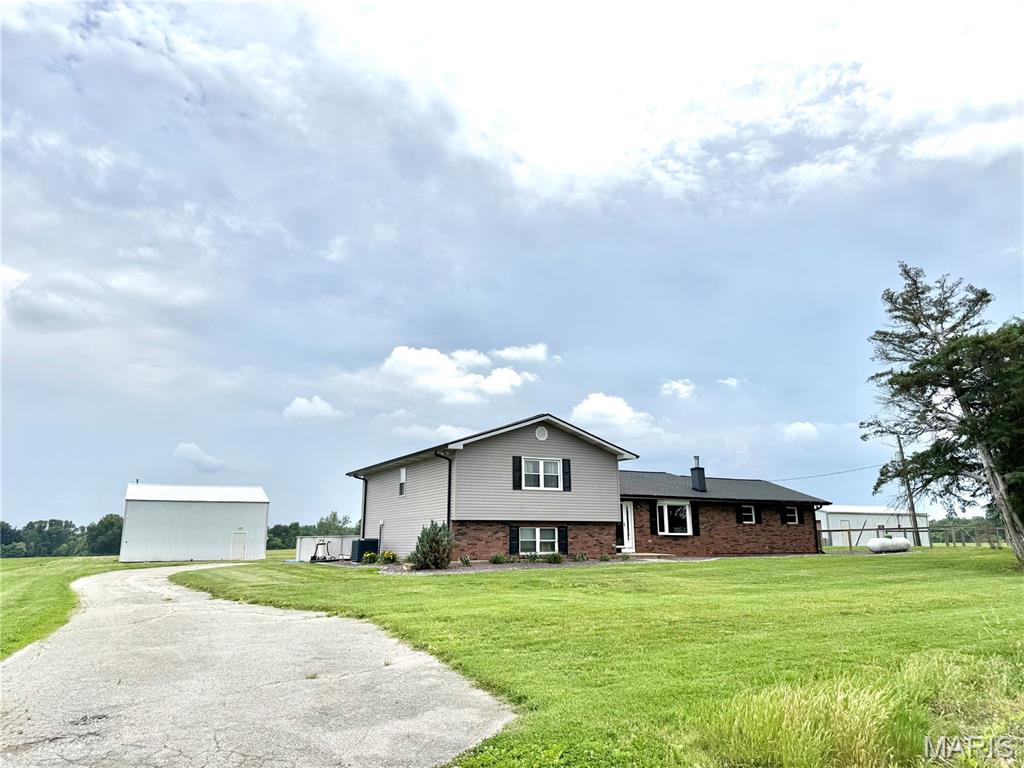 Live off the beaten path, owning 1.96 acres, just minutes from everything while still in O'Fallon School District! This property offers opportunity like few others do. This is a Lebanon address in O'Fallon Township. There are two parcels. With a 0.62 acre driveway separating you from the main road the total acreage is 1.96 and is a dream come true! Brick and vinyl split level homestead features 4 bedrooms and 3 full baths, 39x22 oversized 2 car detached garage with asphalt floor, electric, and well house with UV filter (well pump new 2023), attached 39x12 enclosed carport, and an attached former chicken coop area. There is an additional 32x32 insulated pole barn with concrete floors, power, compressor & outdoor fridge, door heights are 13' and 11'. Ample asphalt parking. House and both garages are each on their own power meters (three total). Primary parcel is 1.34 acres. First level den has double doors and would be perfect for home office, home gym, movie room - you name it - newer vinyl plank floors and easy access dog door leads out to the fenced yard which connects to the detached garage. Main level is where you'll find the kitchen with large pantry and newer stainless LG appliances that includes refrigerator, microwave, electric range, dishwasher, and there is a disposal! Dining area is adjacent the kitchen and leads out new sliding glass doors with built-in blinds to the newer composite deck and above ground pool. Back inside the living room you'll find a wood burning stove. Three good sized bedrooms and two full bathrooms upstairs. Fourth bedroom, third full bath, office/bonus room, laundry and utility rooms in the lower level. Many updates - including but not limited to interior doors, toilets, kitchen sink and counters, and appliances in 2020! HVAC replaced in 2020. Roof, gutters & siding new in 2021. Water heater new 2024. Septic riser new in 2024.  Located moments from interstate access, SAFB, Metro Rec Plex, Downtown O'Fallon and more... properties like this do not come available every day. Schedule now, showings begin Thursday!
