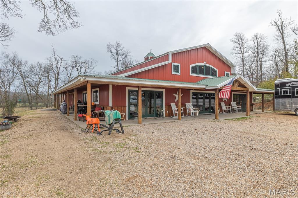 Escape to your dream country life! This stunning barndominium on 13 +/- acres just outside Doniphan offers the perfect blend of rustic charm and modern luxury, with the Current River just a stone's throw away. Equestrian enthusiasts will love the 2 run-in sheds, safe panel paddocks, hay shed, and indoor horse stalls with automatic fly sprayers. The property also features a spacious outdoor riding arena, and a live creek that runs through the entire property, ensuring a constant water source for your horses. For your guests, there are two camper hookups and a concrete pad ready to go. Relax on the wrap-around porch (equipped with its own fly spray system!), find peace of mind in the concrete safe room, and enjoy year-round comfort with geothermal heating/cooling, spray foam insulation, and heated floors. The expansive loft offers endless possibilities for customization – extra bedrooms, a studio, you name it! Enjoy the privacy of a private road, while still being just minutes from the grocery store, gas, post office, and river access. This property offers a tranquil country setting just minutes from all the amenities of town and is a must-see to truly appreciate all it has to offer.