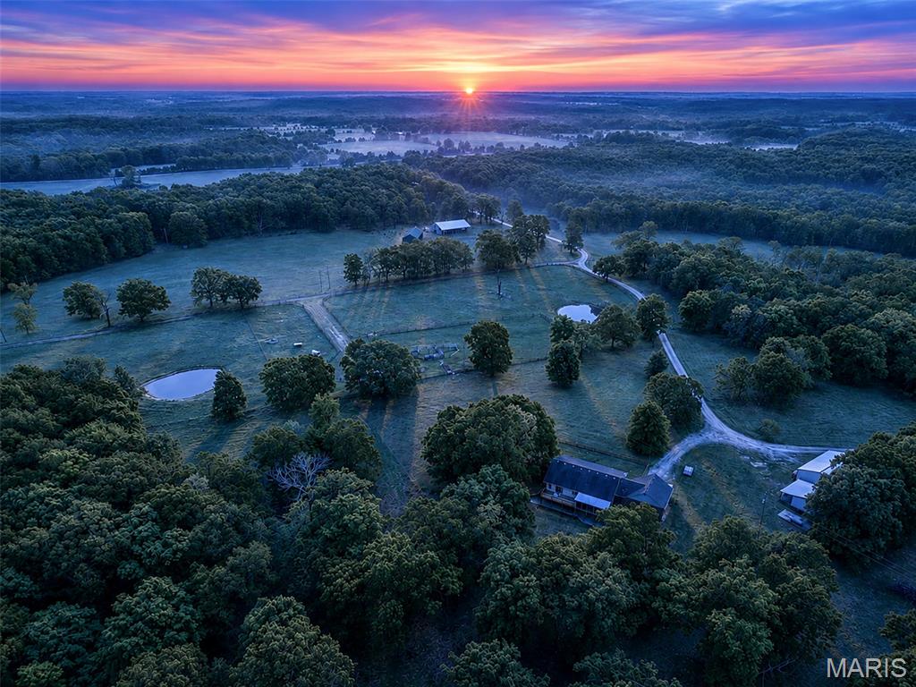Welcome to Grazer Farms - a skillfully planned and turn-key regenerative farm in the heart of the Ozarks. These gorgeous 285 acres offer countless opportunity: Two walk-out-basement homes, cabin, three large workshops, four wells, six stocked-ponds, a 3-acre spring-fed lake with pavilion and swim dock, commercial kennel, steel pipe corrals, pole-barns, mobile offices, tack-room, lean-tos, round pen and efficient cattle working system. The farm has been meticulously designed with electric perimeter and cross-fencing throughout, along with underground freeze-free water lines with quick-connect access points distributed through every portion of pasture. This affords unlimited paddock creativity and the ease of moving animals with a single person. Primarily a cattle, sheep and pastured poultry farm, it can also support horses, goats, pigs or bison. The land is abundant with wildlife. Deer graze outside the kitchen windows. Large groups of turkey and coveys of quail roam about. The lake and every pond are stocked with bass, crappie, catfish, bluegill and more. The nearly ½ mile of creek frontage offers secluded beaches for relaxing in the water or even your own private float trip. Vast trails throughout the property are great for hiking, hunting, UTV or horseback rides that make you feel like you've gone back in time. Turn-Key cashflow opportunities include livestock, pastured poultry, hunting leases, hay production, event-venue or Airbnb. Offering to sell as a package with all handling systems, trailers, 4-wheeler, bale-unroller, freeze-free water tanks, Kubota side-by-side, tractor with loader and brush-hog, fencing and watering materials, chicken tractors & brooding equipment, mineral feeders and more.