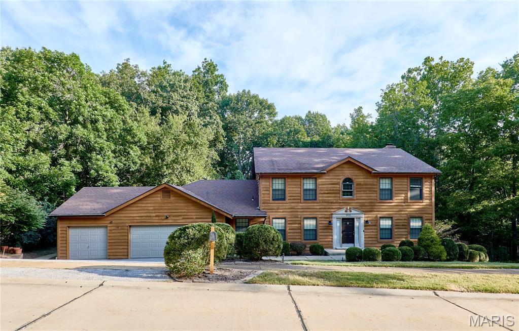 Welcome to this spacious two-story in Wildwood! Nestled on a wooded three-quarter acre lot in the Winding Trails community, this home has the feel of a quiet retreat while just moments from nearby conveniences. You'll love the curb appeal, with great landscaping, a three-car garage, and wood siding. The two-story foyer features wood parquet floors and a beautiful wood staircase. It opens to the dining room on the left and formal living room to the right. Thoughtful details include wood millwork, crown molding, and chair rails. The great room is perfect for entertaining, with a brick-surround woodburning fireplace, bay window, and granite wet bar. The kitchen boasts white cabinets, stainless steel appliances, a double wall oven w/stone surround, breakfast bar, and gleaming hardwood floors that continue into the vaulted breakfast room. A half bath w/pedestal sink and convenient laundry room complete the main level. Upstairs, the vaulted primary suite features a walk-in closet with organizers, dual-sink vanity, tub and separate shower, and ceramic tile flooring. Three more spacious bedrooms and another full bathroom round out the space. The walk-out, finished lower level adds a large rec room, plus unfinished storage and a bathroom rough-in. New HVAC gives peace of mind. Enjoy the last days of summer in the amazing backyard! Gather with friends and family around the fire pit or on the basketball court, or just take in the surrounding nature on the patio with built-in benches. In a great location moments from Rockwood Schools, all of the shopping and restaurants along Manchester and Clayton, as well as community parks and Babler State Park, this home is one you won't want to miss!