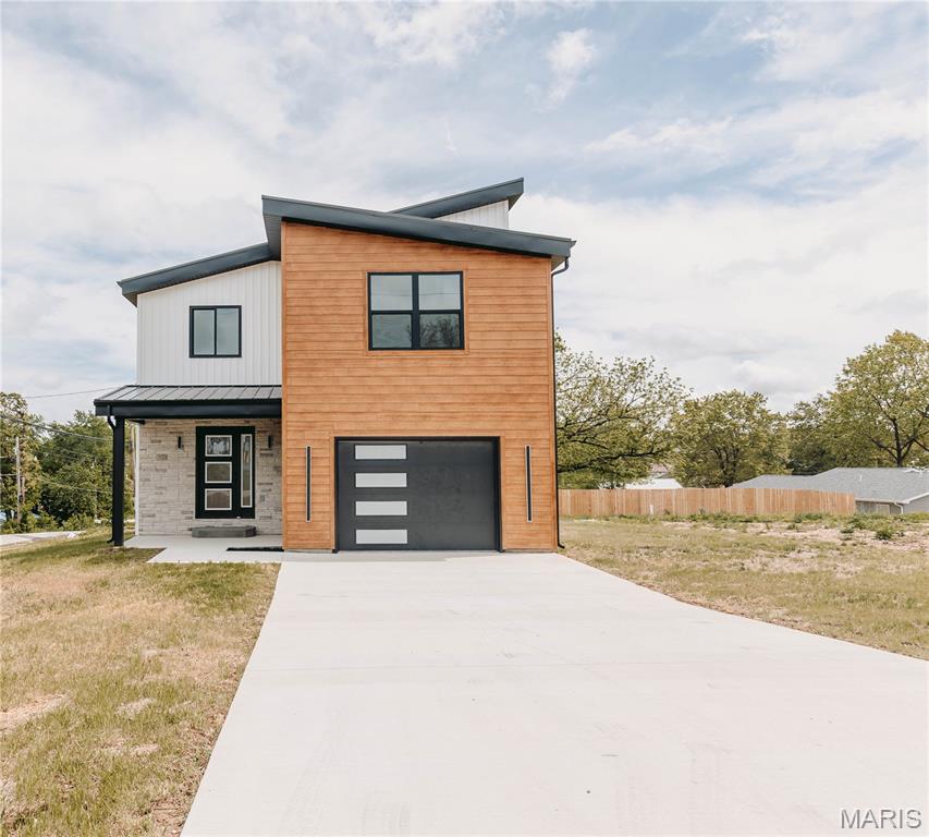 Modern new construction with high-end finishes, vaulted ceilings, and a layout designed for everyday living. This 4-bedroom home offers a functional floor plan with bright, open spaces throughout. The foyer welcomes you with a staircase featuring wood-finish risers, carpeted treads, and a contemporary cable railing system, accented by gold-tone fixtures. The main level connects the great room, dining area, and kitchen. The kitchen includes a large island, quartz countertops, black farmhouse sink with a spring-neck faucet, upgraded black stainless appliances, a black-framed pantry door with frosted glass, and built-ins with coffee bar potential. The dining area is surrounded by windows with quick access to a covered composite deck. A main-level half bath off the foyer features marble tile and upgraded millwork. Upstairs includes four bedrooms, a laundry room with double windows, and an open landing suited for a sitting area or flex space with a statement light fixture. The hall bath features a dual vanity with quartz countertops, and brass-tone fixtures. The primary suite includes high ceilings, large windows, a walk-in closet with built-in shelving, and a private bath with a freestanding soaking tub with a floor-mounted faucet and handheld sprayer, a tiled walk-in shower with glass enclosure and rain shower head, and a dual vanity with gold-tone fixtures. Second-level rooms feature slanted vaulted ceilings with upper windows providing natural light. Additional features include a walk-in pantry with built-ins, under-stair storage, and double-door hall closets near the secondary bedrooms. The primary suite is positioned separately for added privacy. The garage includes a paneled door with frosted glass inserts, recessed lighting, and a window for natural light.