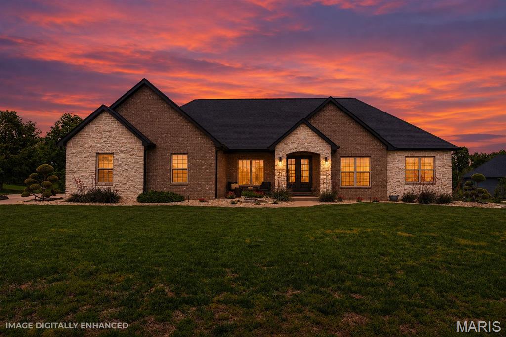 This stunning custom executive estate was designed for luxury and built for comfort! Thoughtful design with extensive high-end upgrades throughout the 3,600+ finished sq ft makes this entertainer’s dream truly stand out. The grand entrance to the Stonehenge subdivision, paired with the beautiful circle drive, makes this Columbia’s most unique subdivision.

As you make your way to the front door, you will fall in love with the picturesque landscaping complete with lighting, exclusive plants, perfectly manicured trees, and a covered front porch with a stone archway. Once you step inside, take note of the 9-foot ceilings and real oak solid hardwood floors that span throughout the main-level living space.

Enjoy views of the beautiful lake from your cozy living room featuring a stone fireplace flanked by custom shelves and cabinets where you will find the smart system controls. Next, notice the archways leading into the gourmet kitchen featuring quartz countertops, floor-to-ceiling custom cabinets, recessed and under-cabinet lighting, Counter Depth full-size refrigerator and freezer, a 42” commercial-grade hood over the oversized 5-burner cooktop, and a walk-in pantry with motion lighting.

The dining room, filled with natural light from loads of windows, provides the perfect backdrop for entertaining or a quiet family dinner. Afterwards, find yourself on the 20x18 covered patio (pre-framed for a potential 3-season room), where you can listen to your favorite music through the built-in speakers or simply enjoy the sounds of nature.

Make your way to the primary suite to find an in-ceiling Paradigm speaker system, TV connection to the whole-house audio system, tray ceiling with wood plank finish, and a barn door leading to the spa-like ensuite complete with dual vanities (with outlets under the cabinets), a large tile walk-in shower, soaking tub with remote-controlled shade, and a separate toilet room with linen storage.

Enter the oversized walk-in closet to find a pocket door leading to the laundry room with an oversized sink, folding table, and extra cabinetry. A private office with French doors sits just off the foyer, where you can enjoy views of the second lake at the front of the home.

Two additional bedrooms and a nicely appointed full bath with added storage in the extra-deep linen closet can also be found on the main level.

And just when you thought you had seen it all, find yourself in awe of the finished lower level. Hand-painted brick accent walls, angled LVP flooring, flush-mounted lighting, in-ceiling speakers, painted ceilings with upgraded industrial-style vents, crown molding details, USB outlets, archways, and added soundproofing are all showcased in the custom bar and entertaining area featuring a custom concrete bar.

With 3 egress windows, you won’t believe you are in the lower level of the home. Bedrooms 4 and 5, another full bath, and plenty of unfinished storage space complete the lower level.

The oversized 24x36 side-entry 3-car garage features an extra-wide 18-foot insulated door, speakers, windows, and extra blown-in insulation, offering plenty of space for all your toys.

The Control4 system operates speakers throughout the main level of the house, exterior lighting, home theatre, and internet, all from your mobile device. The main level is also wired with CAT-6 for door security, motion detection, and lighting automation that can be added to the system.

Blending timeless style with modern convenience, this remarkable home is everything you have been dreaming of. Call today for a full list of upgrades or to schedule your private tour.