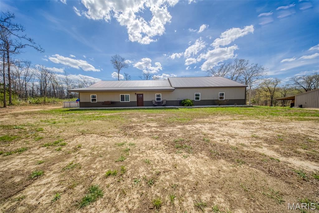 Discover the perfect blend of comfort, functionality, and outdoor living with this 3-bedroom, 2-bath home nestled on 9.75 m/l mostly wooded acres—an ideal setup for nature lovers and hunting enthusiasts alike. Offering approximately 2,000 square feet, this slab home features durable metal siding and a metal roof, along with quality Jeld-Wen double-pane windows for efficiency and peace of mind. Inside, the spacious great room welcomes you with a cathedral ceiling and tile flooring, creating an open and inviting atmosphere. The kitchen is thoughtfully designed with custom hickory cabinetry complete with soft-close features, lazy Susans, pan drawers, and a built-in trash drawer. A stainless steel apron front farmhouse sink, large island with additional storage, walk-in pantry, and stainless steel appliances make this space as functional as it is stylish. The primary suite offers a private retreat with a jetted tub, double vanity, separate shower, and tile flooring. A large laundry/mud room adds convenience and practicality for everyday living. Step outside to enjoy the 24’ round above-ground pool with deck, a dedicated fire pit area, and abundant wildlife—making this property an excellent hunting setup. The outdoor wood furnace even heats the attached 3-car garage, adding extra efficiency during cooler months. Additional highlights include a shared well and driveway. Please note: air compressor and lift in the garage do not convey, and the chicken coop is excluded from the sale.
