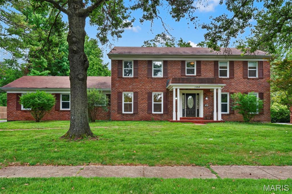 Timeless Colonial style home with classic brick elevation and traditional symmetry, thoughtfully expanded for modern living. Classic design meets everyday comfort in this beautifully maintained home featuring a spacious tiled entry foyer, flanked by formal living and dining rooms—perfect for both entertaining and flexible living. The kitchen offers rich dark wood cabinetry and solid surface countertops, flowing seamlessly into the inviting den anchored by a wood-burning fireplace with brick surround. A convenient powder room sits just off this space. Sliding doors lead to a large patio overlooking a level, private backyard surrounded by mature trees—ideal for outdoor living and relaxation. The main level also includes a generously sized laundry room with service door to the backyard and access to the rear-entry 2-car garage. Upstairs, you’ll find four spacious bedrooms, including an owner’s suite with private bath and dual closets. A full hall bath with tub/shower and linen closet serves the additional bedrooms. The partially finished lower level expands your living space with a large rec room, kitchenette area, and two additional rooms perfect for a home office, craft room, or hobbies. 
Nestled on a quiet cul-de-sac in a desirable location with top-rated schools, this home offers space, privacy, and a traditional layout designed for today’s lifestyle.