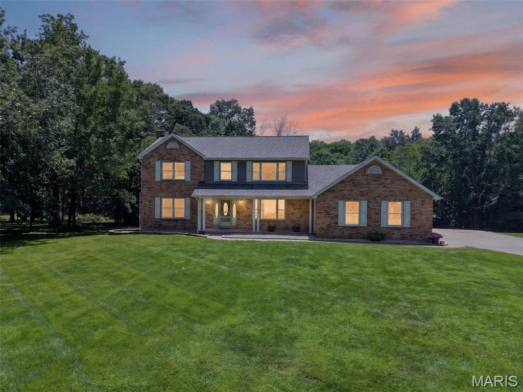 Welcome to 10 Woodleaf Court, which sits on 3.47 wooded acres. This two-story brick traditional, built in 1989, has a covered front porch and an attached three-car garage big enough to park all your toys. The lot backs up to trees on three sides, so the house sits well back from the road with a deep, front lawn and a wooded buffer around it. It's in the Fort Zumwalt North school district, just minutes off Highway P, on a quiet stretch of Woodleaf Court.

Inside, the main level opens into a living room built around a wood-burning stove on a full brick surround, with hardwood floors running the length of the room. The kitchen has a corner sink under its own window, with custom-stained cherry wood cabinetry, tile backsplash, stainless steel appliances, and a peninsula with seating for two. It opens straight into a breakfast nook with a bay window and a door out to the back patio. A separate formal dining room sits off the kitchen. Main-level laundry and a half bath round out the first floor.

Upstairs, the primary bedroom has a vaulted ceiling with an exposed wood beam and an ensuite bath with a soaking tub and a separate glass-enclosed tile shower. Three more bedrooms and a full bath complete the level. Downstairs, the basement has a finished full bathroom; the rest is unfinished with a full 8-foot pour and walk-out access, so there's room to build out if a future owner wants it.

Some of the less visible work is already done. The roof was replaced in June 2026. The foundation had a few cracks professionally repaired in October 2021 with no issues since. Both second-floor bathrooms have been fully remodeled. Both HVAC units were just serviced. Water is well, sewer is septic.

This is a house for someone who wants to enjoy country living with all the amenities of being in town. Three and a half acres of trees and yard in this school district, at this price, doesn't come up often.
