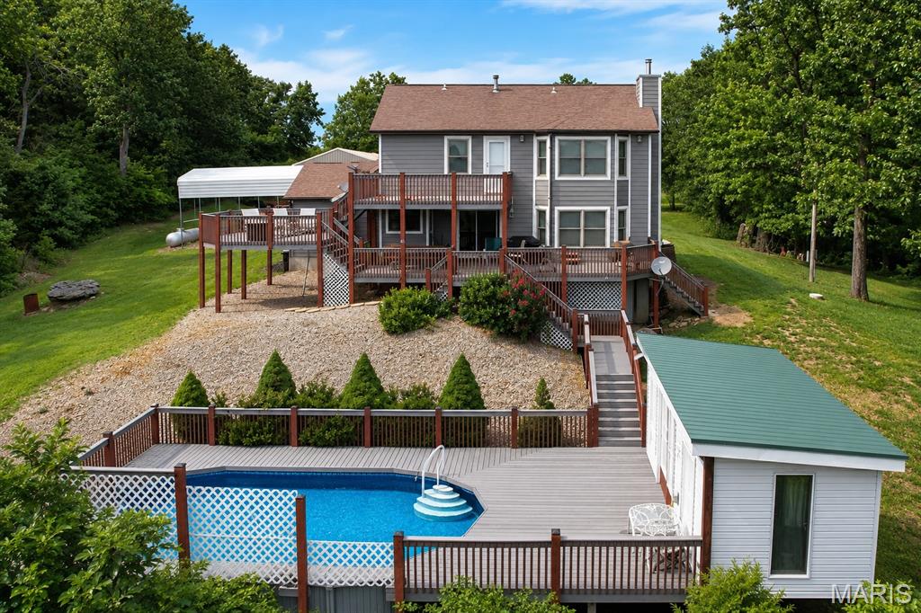 Nestled among mature trees with one of the best views in all of Warren County. This spacious 2-story home offers 4 bedrooms, 3 full baths, a dedicated office, and a finished walkout lower level. The main level features a large family room with fireplace insert, separate dining room, main floor laundry, and an eat-in kitchen with custom cabinetry, breakfast bar, pantry, and sliding door access to the multi-level deck. Upstairs, the primary suite includes a walk-in closet and private bath with double vanity, separate shower, and jetted tub, along with three additional bedrooms.

The finished walkout lower level provides exceptional flexibility with a large recreation room, bonus room, full bath, and dedicated canning room. Enjoy outdoor living from the covered front porch, beautifully landscaped grounds, multi-level deck, and above-ground pool, all surrounded by mature trees and peaceful wooded views.

Car enthusiasts, hobbyists, and small business owners will appreciate the attached 2-car garage, camper carport, and the impressive 30' x 72' four-bay, 5 car garage outbuilding featuring approximately 48 feet of finished, heated space with electric and a 2-post lift. Additional updates include a new well pump in 2025, new hardie board siding, new windows, newer water heater, owned 500-gallon propane tank, central vacuum system, and quality 4-panel wood doors throughout. Built in 1989, this property offers the space, functionality, and versatility that are increasingly difficult to find.