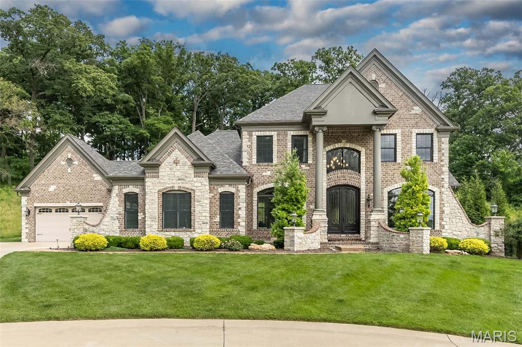Tucked away on a premier half-acre cul-de-sac lot with a breathtaking wooded backdrop, this exceptional estate offers over 5,600 square feet of beautifully finished living space in one of Chesterfield's most sought-after locations. From the moment you arrive, the grand circular drive, stately brick and stone exterior, and commanding presence set the stage for a home that is both elegant and inviting.

Step inside to discover a dramatic two-story entry and spectacular great room, where soaring ceilings, a stunning floor-to-ceiling stone fireplace, a sweeping open staircase, and walls of windows create an unforgettable first impression. Rich architectural details, extensive millwork, and abundant natural light flow throughout, while the open-concept design seamlessly connects the home's gathering spaces.

At the heart of the home, the chef's kitchen was designed for both everyday living and effortless entertaining. Featuring custom cabinetry, premium appliances, generous prep space, a massive center island, and walk-in pantry, it opens beautifully to the breakfast room and great room, ensuring family and guests remain connected at every gathering.

The thoughtfully designed floor plan offers a luxurious main-level primary retreat complete with a spa-inspired bath and spacious walk-in closets. Upstairs, three generously sized bedrooms and two full baths provide comfort and privacy, while the finished walkout lower level features a private guest suite and full bath, creating an ideal space for visitors or multi-generational living.

Designed for grand-scale entertaining, the lower level is truly extraordinary. A custom pub-style bar with striking stone and brick accents serves as the centerpiece, complemented by expansive recreation spaces and a private theater room that rivals the experience of a boutique cinema. Whether hosting game day gatherings, holiday celebrations, or intimate evenings with friends, this level was built to impress!

The outdoor living experience is equally remarkable. A stunning covered lanai with a stone fireplace overlooks the private wooded setting, creating a year-round retreat for relaxing, dining, and entertaining. The peaceful backdrop and exceptional privacy offer a rare sense of seclusion while remaining conveniently close to everything Chesterfield has to offer.

Recent improvements provide tremendous value and peace of mind, including a recently installed roof, gutters and exterior paint  June 2026, refinished hardwood flooring on the main level 2026, new carpet upstairs 2026, new luxury vinyl plank flooring in the lower level 2026 and fresh interior paint. Sellers have already scheduled new garage doors to be installed also!

Offering 5 bedrooms, 4.5 baths, a 4-car garage, and an unmatched combination of luxury, craftsmanship, privacy, and thoughtful updates, this is more than a home, this is the lifestyle you deserve!