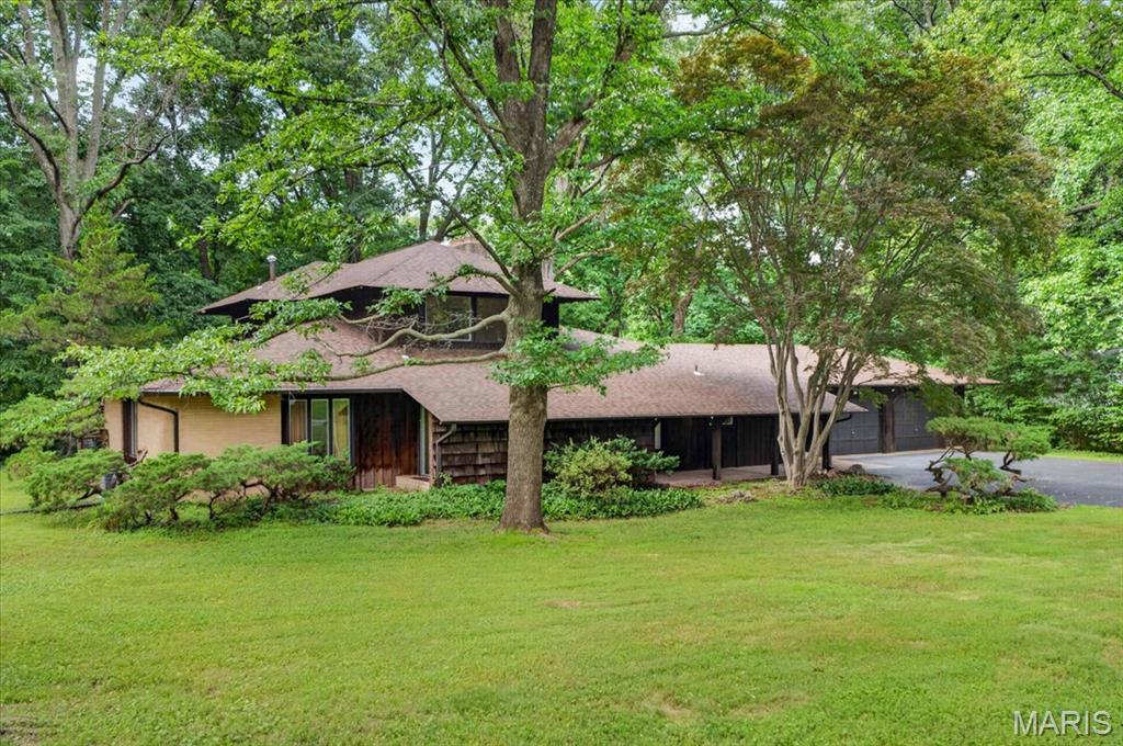 A rare mid-century modern masterpiece on over an acre in River Bend Estates, this 1968 architectural jewel offers 4 bedrooms, 3.5 bathrooms, and 3,063 square feet of organic design, lovingly preserved by just three owners in nearly six decades. A stunning original wood front door leads into a dramatic entry foyer, opening to a sunlit floor plan anchored by a magnificent two-sided brick fireplace that warms both the formal living and family rooms. Complete with classic parquet wood floors, built-in MCM shelving, and massive windows framing treetop views, every corner honors its iconic heritage. The home flows naturally toward a sunlit breakfast room, which opens to a serene screened porch for seamless outdoor dining. Designed for ultimate flexibility, the layout features dual primary suites—one on the main level opening directly to the private outdoor grounds, and a second-level retreat with a dedicated sitting area and a balcony. Key infrastructure updates like a newer roof (2022) and high-efficiency HVAC provide peace of mind, leaving you free to customize the remaining spaces to your personal style. The flat acre+ lot backs to woods creating an exceptionally private space that features a sprawling brick patio made for entertaining. A partially finished basement ready for a gym or media room, main-level laundry, and an oversized two-car garage round out this amazing home. Located in the highly sought-after River Bend neighborhood where a vibrant community center with a pool (optional annual membership/fees apply) and year-round activities quickly make friends of neighbors, this home is as welcoming as it is historic.