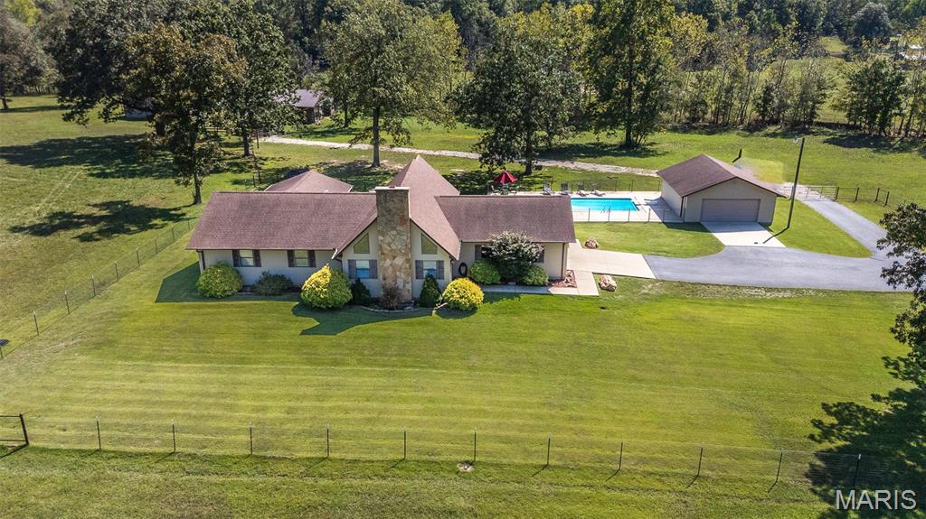 Escape to the ultimate equestrian paradise! This beautiful ranch-style home perfectly combines premium country living with unmatched convenience, located just 5.5 miles from Poplar Bluff.  A smooth, fully paved asphalt driveway welcomes you home.  Dive into your private, sparkling inground pool—perfect for summer relaxation. Features two barns and a tack room with ample room for livestock, hay storage, heavy equipment and storage for all your saddles and riding gear. Two ponds offering natural water sources. The 18-acre +/- property is fenced & cross-fenced and adjoins government land. Step right off your property into hundreds of acres of protected land with direct access for premier hunting, hiking, and miles of trail riding.