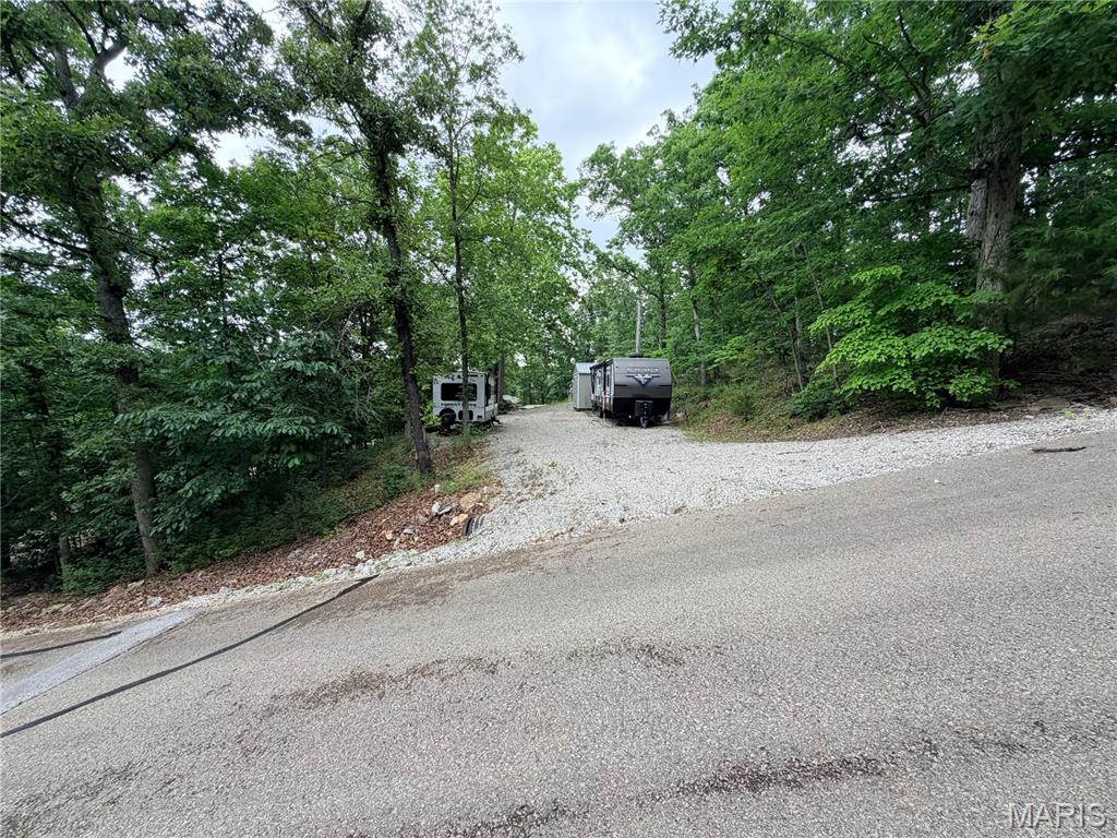 Welcome to an incredible opportunity to own a piece of paradise at the desirable Lake Perry! This property provides a versatile option for your enjoyment, whether you're looking for a full-time camper lot or considering building a home. The half-acre lot provides a serene backdrop for relaxation. The abundance of trees provides the option for a more private setting, and with a bit of clearing, you can tailor the landscape to suit your preferences.  Utilities are already in place for 2 campers, with a 200 amp camper hookup available and water and septic connections on the lot. Large Camper stays with lot - Palomino Puma camper.  Lake Perry, a spring-fed 200-acre lake, provides various activities such as fishing, water skiing, and boating, with several amenities, including beaches, playgrounds, picnic areas, a seasonal restaurant, and an in-ground pool. It's a recreational haven for residents.
