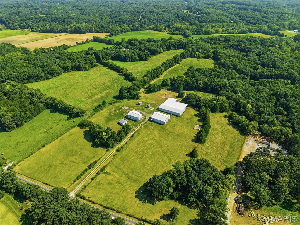 Space to Build. Room to Work. Land to Enjoy. Located in a quiet country setting with blacktop frontage and easy access to both I-70 and Highway 61, this property gives you the freedom to create the lifestyle you’ve been looking for. The acreage features a mix of open pasture and wooded ground, with a pond and excellent wildlife habitat. Deer and turkey are frequently seen throughout the property, while the open ground provides plenty of options for horses, livestock, recreation, or simply enjoying the outdoors. The improvements are what truly set this property apart. There are two substantial insulated, climate-controlled metal buildings, giving you an incredible amount of usable space. The larger building measures approximately 64’ x 50’, while the second measures approximately 54’ x 30’. Both feature concrete floors and overhead doors, making them ideal for equipment storage, vehicle storage, a workshop, hobbies, or a variety of business uses. Additional improvements include a large livestock barn and a detached two-car garage. Whether your goal is to build a custom home, establish a small farm, keep livestock, run a business, or simply have a private place with plenty of room for your equipment and hobbies, this property gives you the foundation to make it happen. Opportunities like this rarely come along with this combination of acreage, location, and improvements. Schedule your private showing today.