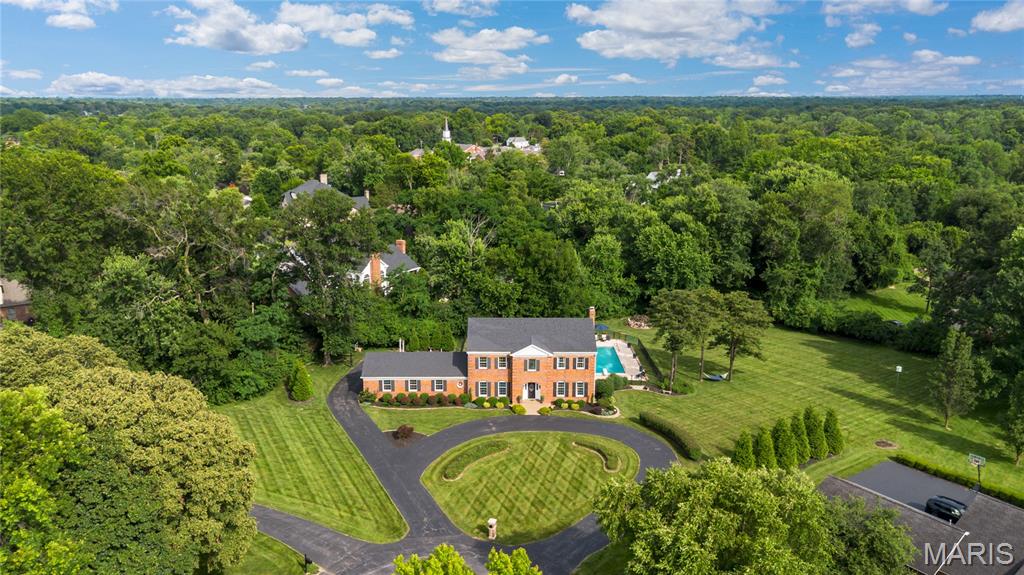 A rare offering of distinction, privacy and scale, this exceptional estate home is gracefully positioned on a secluded 1.3+ acre cul-de-sac lot adjoining beautiful Drace Park. Encompassing more than 4,800 square feet of thoughtfully designed living space, this stately brick residence showcases timeless architecture, superior craftsmanship, and an extraordinary resort-inspired outdoor setting. Constructed by renowned Pettis Homes, the home was built with enhanced double insulation, 9-foot ceilings throughout the main and upper levels, and an enduring commitment to quality. Significant recent improvements—including a newer roof, newer zoned HVAC systems, and a new 75-gallon water heater—provide peace of mind while preserving the home's classic elegance. A sweeping circular drive creates a grand first impression, leading to a dramatic two-story foyer where refined formal living and dining rooms are framed by rich millwork, crown molding, and sophisticated architectural detailing. Designed for both gracious entertaining and comfortable daily living, the expansive floor plan unfolds into a spacious chef’s kitchen featuring a center island, wet bar, generous dining area, and picturesque bay windows overlooking the estate grounds. The adjoining family room serves as a warm gathering space, anchored by a gas fireplace and surrounded by views of the private backyard sanctuary. Beyond the interior, the property transforms into a true private retreat. Surrounded by mature trees and lush landscaping, the resort-caliber outdoor environment offers an in-ground pool, charming gazebo, expansive patios, and multiple destinations for entertaining, dining, and relaxation. The combination of acreage, privacy, and proximity to the park creates a setting rarely found in today's market. The upper level is highlighted by a luxurious primary suite designed as a peaceful escape, complete with a spacious walk-in closet and a beautifully renovated spa-inspired bath. Three additional generously sized bedrooms and multiple updated baths provide exceptional comfort and flexibility for family and guests alike. In total, all six bathrooms throughout the residence have been thoughtfully updated with timeless finishes. The finished lower level further enhances the home's remarkable livability, featuring an expansive recreation and game room, kitchenette, full bath, and versatile spaces ideally suited for guests, a fitness studio, home office, media room, or multi-generational living arrangements. Combining over 4,800 square feet of living space, extensive capital improvements, six updated bathrooms, resort-style amenities, and one of the area's most coveted private settings, this extraordinary property represents a rare opportunity to experience estate-style living in an unmatched park-side location.
