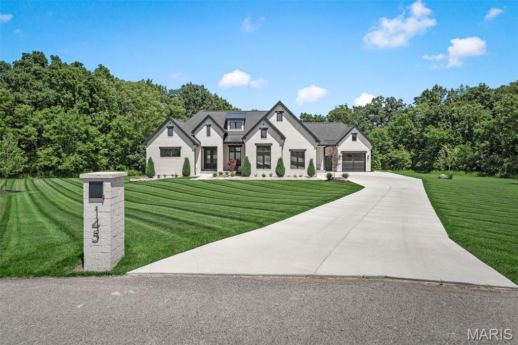 Beyond the quiet cul-de-sac and striking front elevation, an extraordinary modern sanctuary awaits, where absolutely every detail has been masterfully considered. 

Upon entering, you will be captivated by the abundant natural light and serene wooded backdrop, framed beautifully by dramatic black windows topped with transoms. The focal point of the great room is an elegant gas fireplace with a granite surround, set against custom millwork and soaring vaulted ceilings accented by oak beams. The spacious kitchen is a dream for any culinary enthusiast, boasting exceptional cabinet and counter space, premium GE Monogram appliances, and a clever hidden pantry equipped with a drawer microwave and its own counters and storage. The in-formal dining room features floor-to-ceiling windows and an 8' sliding door that opens to an exceptional outdoor living space. This outdoor oasis comes complete with a wood-burning fireplace and retractable power screens, allowing you to seamlessly adapt the space for any occasion. A second uncovered patio offers additional outdoor entertainment space. 

Retreat to the main-floor primary suite, where oak beams highlight the ceiling height and bring warmth to the space, complemented by elegant 64" wainscoting. The spa-like en suite features heated floors, a spacious glass shower and a separate soaking tub. The custom walk-in closet includes built-in shelving, a center island, and direct, convenient access to the laundry room. A second main-floor bedroom with impressive trim detail—currently utilized as a home office—is located on the opposite side of the home with easy access to a full bathroom featuring a custom tile shower.

Downstairs, the impressive lower level is designed for entertainment. It features a rec area, a wet bar with custom cabinetry and a beverage cooler, and unique restaurant-style booth seating alongside a theater room. A dedicated home gym suite includes a walk-in closet and private full bathroom, offering an easy conversion into an additional bedroom suite. On the opposite side of the lower level, two additional bedrooms with full egress windows and a shared full bath complete the lower level. The property features exceptional parking and garage space with both a 22x25 2-car garage and a 20x22 1-car garage. Because we know you absolutely love this home JUST the way it is, all current high end furnishings are included (please inquire for list)!!