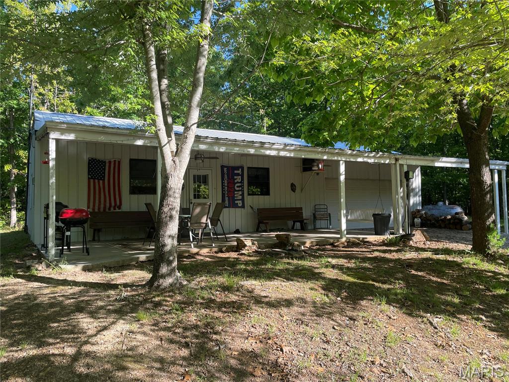 If you are looking for the cabin in the woods, this is the property for you.  The cabin features 3 bedrooms (2 non conforming), 1 bathroom with shower only, open living room/kitchen, utility room and 2-car attached garage with automatic garage door opener, storage shelves, 220 and 110 electric outlets.  Metal roof, metal siding and gutters with gutter guards.  All the conveniences of being right at home including propane forced air furnace, central air and 5 ceiling fans.  Enjoy the covered front porch with ceiling fans and tv hookup.  Sit out here and watch it rain or just listen to the night sounds.  On the cool nights, step inside and enjoy the wood stove.  Small metal storage building.  The acreage is perfect for hunting deer and turkey, riding side by sides/4 wheelers or just enjoying nature.  There are 2 ponds with one being stocked for fishing if you choose to do so.  A couple open areas, one with apple trees, that would be perfect for food plots or just leave it natural and enjoy the old shooting range.  Many trails throughout the property that can be accessed with a four-wheeler or side by side.  The water system is a 1000 gallon, concrete cistern with a pump set up to provide water to the house just like a well.  It also has a rain catch barrel with a sand filter that flows into the cistern.  This property is being sold with contents of the house and garage including a small tractor with bushhog and blade, riding mower, push mower and multiple tools.  Sellers will keep a few personal items.  You don't even have to move anything but yourself to start enjoying this property from day 1.