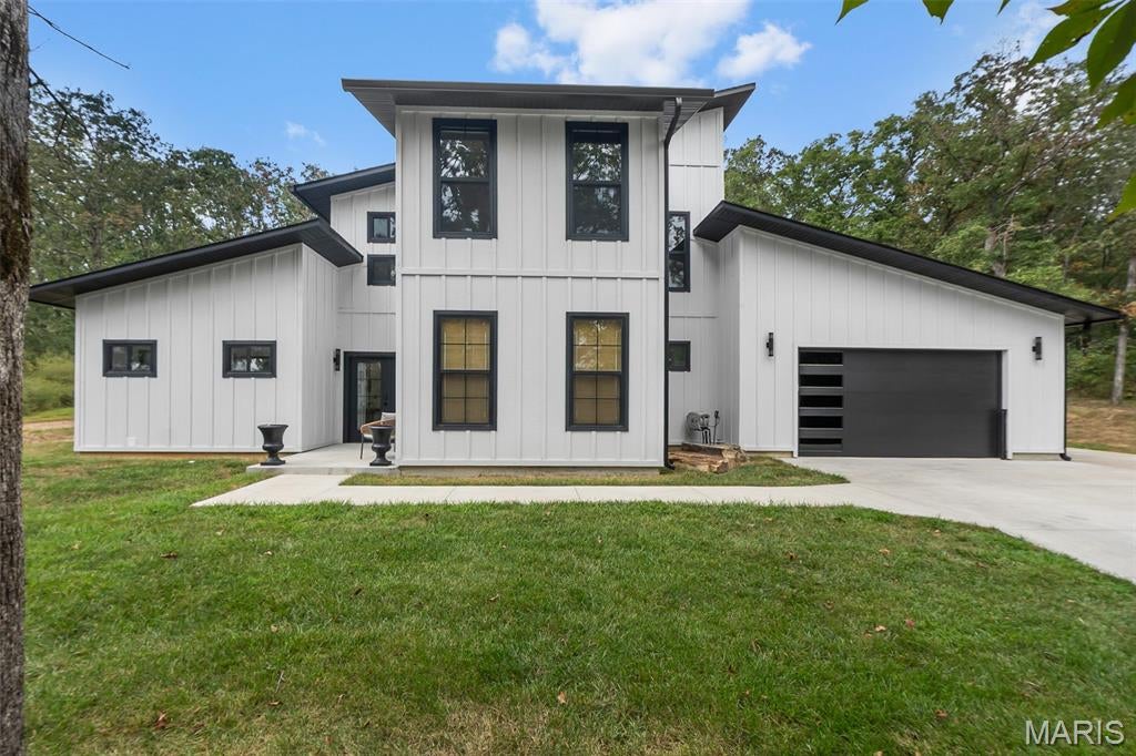 Modern, custom, and unlike anything else on the market! Located in Deer Run Estates, this 4 bedroom, 2.5 bath contemporary home offers 2,387 finished square feet and was built just 2 years ago. Step inside to a wide open main living area with soaring ceilings, exposed wood beams, an abundance of windows, solid-surface flooring throughout, and a custom floating staircase that immediately sets this home apart. The kitchen features floor-to-ceiling cabinetry, a large center island, Samsung Bespoke glass appliances, gas range and a separate butler's pantry, all opening directly into the living and dining areas. The main floor master suite offers a spacious retreat with a large walk-in closet that doubles as the laundry room, making everyday living that much easier. An additional main floor bedroom provides the perfect setup for guests or a home office. Upstairs, the custom staircase leads to an open loft/sitting area overlooking the main living space, along with two additional spacious bedrooms and a full bath. Outside, the home's modern white-and-black exterior is surrounded by a wooded 0.99 acre lot featuring unique natural rock formations behind the home with plenty of possibilities for creating your own outdoor space. The attached 800 sq. ft. garage is fully insulated and drywalled, providing plenty of room for vehicles, storage and more. Enjoy everything Deer Run Estates has to offer, including fishing, boating, swimming and kayaking. Conveniently located between Fredericktown and Farmington, this nearly new home is ready for you to move right in and enjoy!