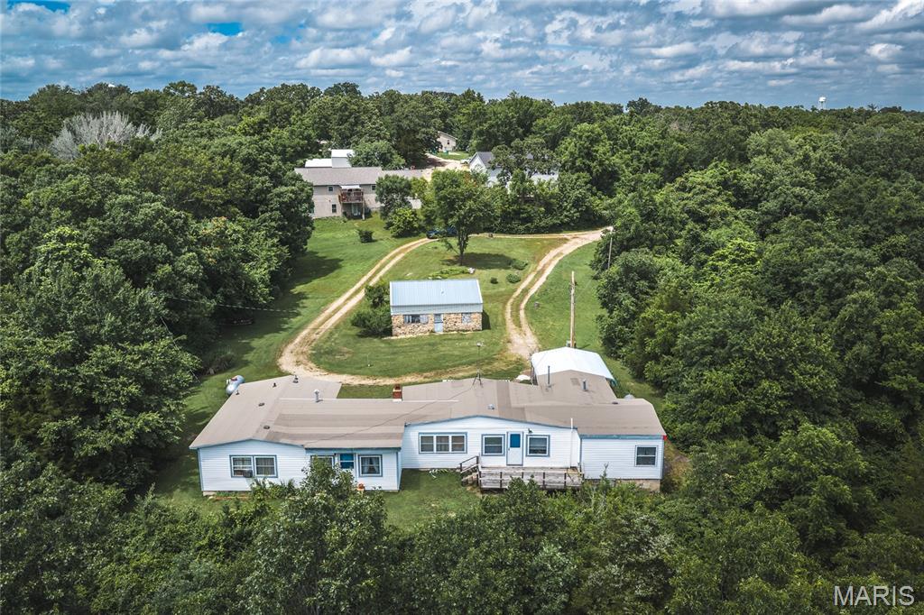 A rare find inside city limits! Approximately 14+/- serene, park-like acres offering an incredible combination of privacy, space, wildlife, and convenience. Tucked away with a secluded, country feel yet located right in town, this unique property offers endless possibilities.

The residence has previously been utilized as a duplex, providing excellent flexibility for multi-generational living, rental income, separate living quarters, or conversion to a spacious single-family home. Generously sized rooms, abundant storage, and beautiful Northern cedar planks—approximately 60 years old—on the walls and ceilings give the home warmth and character you simply don’t find in newer construction.

The property has also been thoughtfully maintained for efficiency, featuring vinyl siding and windows, blown-in insulation added in 2010, and a new roof in 2024. A wood-burning insert provides an additional cozy heat source. The 2-car carport could easily be enclosed to create a full garage.

Major features and updates include a large 220V window A/C unit (2015) capable of cooling the entire home, propane furnace (2010) serviced annually, propane water heater (approx. 2010), ductwork cleaned 11/24, new toilet 4/25, and stainless double sink with new kitchen faucet 10/25. Side B offers a newer electric water heater, white cast-iron double sink with new faucet (10/25), propane furnace (2010), and ductwork cleaned 10/25.

Adding even more versatility, the property includes two city utility hookups with a third that can be readily adapted, along with two MFA propane tanks with new regulators.

The rock house adds another layer of potential, featuring concrete floors, a garage-style door, and new rafters and a metal roof installed in 2010. Whether envisioned as a workshop, storage space, hobby area, or something more, it complements the property’s flexibility beautifully.

With mature trees, open areas, abundant wildlife, and a peaceful, tucked-away setting, this property feels worlds away while keeping the conveniences of town close at hand. Whether you’re searching for a private homestead, multi-generational property, income-producing opportunity, or one-of-a-kind investment, 14+/- acres inside city limits is an opportunity that rarely comes along.

Property is being sold AS-IS.