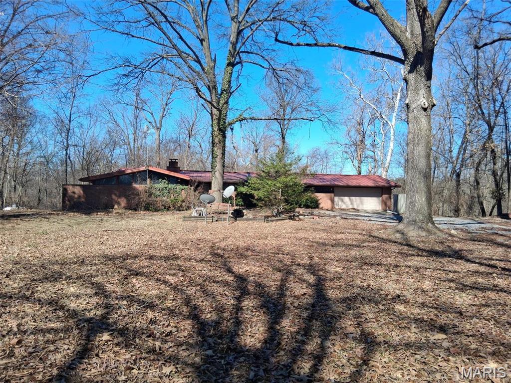 Zoned residential or commercial - This property is perfect for a counselors office who is looking for a location with peaceful town and country feel to relax their clients, a law firm, a spa, a small event center, and more! The 2,200SF existing home could be renovated to conform to your use, or redevelop the site into your dream office. The building is located in the center of a 7.23 acre wooded lot, with additional room to develop. Signage along Highway 159 would direct your client/customers to a space that is not visible from the 159, but offers a unique atmosphere which feels like you are visiting a weekend, outdoor retreat.
Property needs interior rehab

Property is on a well and septic but buyer will be required to install new water line and sewer line 
per the Village of Maryville

The past use was residential, but the property is now zoned commercial which opens the path to several uses, not previously approved by the City. Located between Interstates 55 and 270, this property is easily accessible from all directions. 1.5+ acres of the 7.23 acre site is level/slightly sloping, that could be used for additional buildings or redevelopment. Water and Sewer will need to be ran and connected to the site, per the City of Maryville.