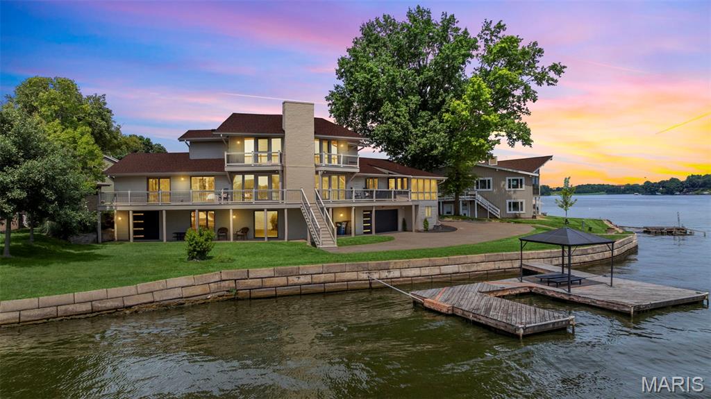 GORGEOUS Waterfront home perfectly situated on cul-de-sac with 200 Feet of shoreline on Lake Saint Louis. Step inside & be instantly captivated by panoramic views of Lake St Louis from the Great Room featuring brand new wood-grain tile flooring, wire cabling railing & custom tile accent wall. The completely remodeled chef’s kitchen is a showstopper—designed w/a massive quartz center island with seating, custom cabinetry, walk-in pantry, beverage fridge, & stainless steel appliances including double wall oven— all open to the formal dining room which includes a built-in wet bar - both ideal for entertaining or casual family meals.  Two bedrooms (new carpeting being installed next week) & a full bathroom complete the main level. Upstairs you will find the master suite w/more sweeping lake views & master en suite ready for it's makeover! (Cabinetry and tile to match kitchen already on site!) Downstairs you will find a Rec-Room, additional bedroom, full bathroom, laundry room & golf cart/toy/storage garage. Third bay garage ready to be installed by new owner w/matching door. Enjoy evening sunsets on your screened in porch, composite deck, huge dock or dropping your boat in off your ramp! Seawall is in great condition! New paint, tinted windows, high end finishes & breathtaking views provide lake living at it's finest along with all the amenities - Restaurant & Bar,  Two Swimming Pools, Sand Beach, Par 3 Golf Course, Pickleball & Tennis Courts & so much more!