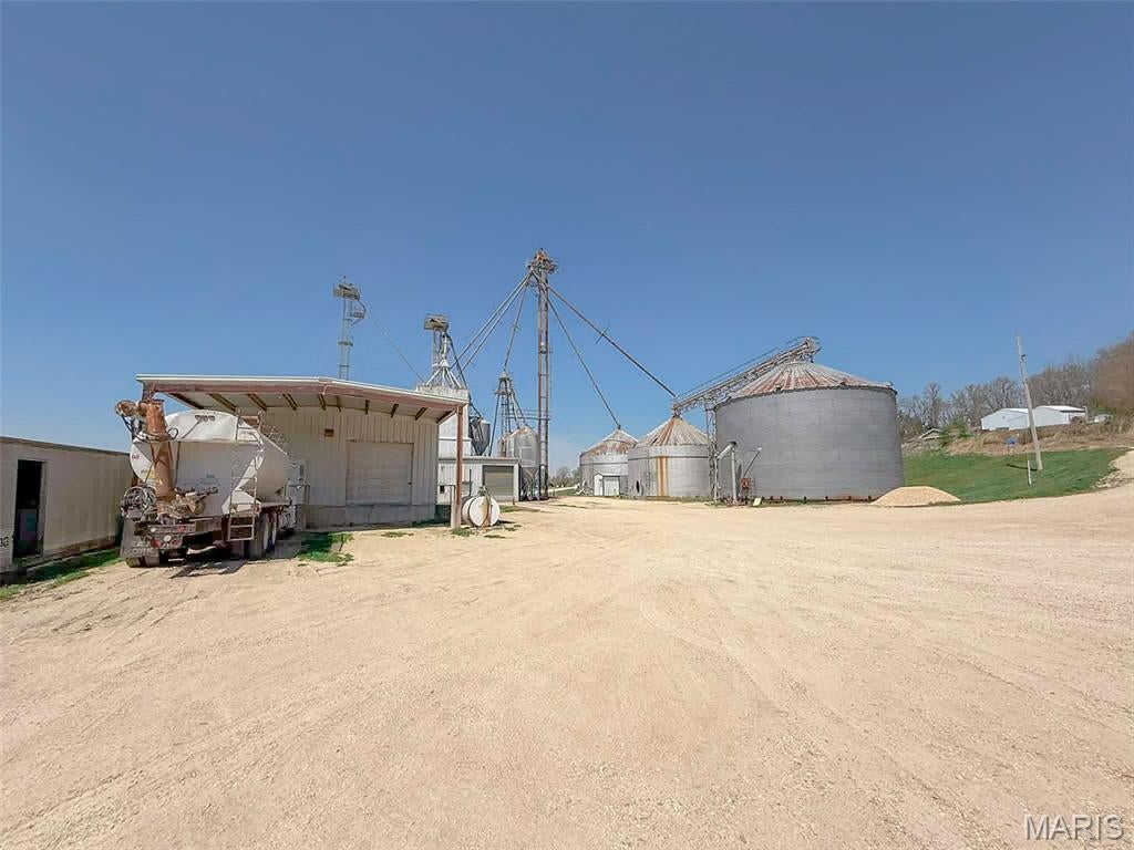 Operating Agricultural Feed Mill Facility on 2± Acres
Currently operating, this turnkey commercial feed mill facility offers approximately 130,000 bushels of total grain storage capacity, presenting a strong opportunity for continued agricultural use or investment. Situated on approximately 2 acres, the property features a functional layout with established grain handling infrastructure and support improvements designed for efficient day-to-day operation. Grain storage is highlighted by one 56,000 bushel steel bin and two 26,000 bushel steel bins, providing substantial core capacity. Additional infrastructure includes a 10,250 bushel grain bin and a 10,000 bushel cone tank, along with multiple premix bulk tanks, ingredient bins, and overhead load-out bins, offering flexibility for a variety of feed and grain applications. The facility includes a feed mill building with attached office and receiving area, along with a steel-framed warehouse of approximately 3,600+ square feet, complete with loading dock and canopy to support efficient shipping and receiving. Recent updates and improvements enhance the overall functionality of the facility, including a newer roller mill system installation, updated ingredient bins, and grain bin improvements such as floor and unloading system upgrades. These enhancements contribute to a more efficient and usable operation for future ownership. Additional features include a truck scale, load-out area, augers, and a well-designed layout that accommodates commercial traffic flow. Forklift to remain with the property, adding immediate operational value for the next owner. This property presents a strong opportunity for feed production, grain handling, or repurposing into a variety of agricultural or light industrial uses, with key infrastructure already in place. Located in the heart of the Midwest, this area has a strong farming presence and supports consistent demand for feed and grain services.