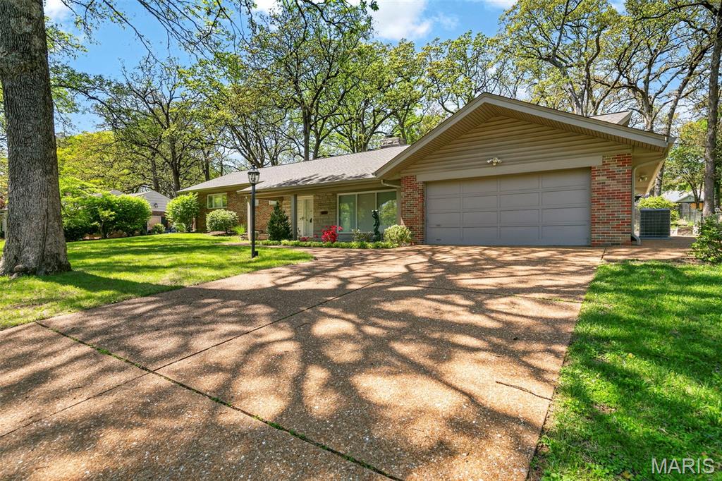 Discover a truly unique floor plan set on a beautiful, open lot just under half an acre in the heart of Grantwood Village, within the highly sought-after Lindbergh School District. This 3-bedroom, 2-bath brick home offers a rare blend of mid-century character and modern updates, all surrounded by exceptional outdoor space.
The kitchen is a standout, featuring granite countertops, white retro steel cabinetry, stainless steel appliances, a center island, pantry, and recessed lighting, perfectly blending vintage charm with modern convenience. The sunken living room with indirect lighting and large picture window makes this a one of a kind setting.  Both bathrooms have been tastefully updated, including one with a delightful retro garden tub that adds character you won’t find in today’s new builds.
An exposed aggregate driveway leads to the two car garage and enhances curb appeal, complemented by covered soffits and fascia and a full irrigation system for easy maintenance. Inside, the spacious family room features a walk-out to the expansive backyard, creating a seamless connection to the outdoors. Enjoy entertaining or relaxing on the newer patio, overlooking the large, private yard with endless possibilities.  Improvements include new patio in 2023, Roof and Gutters replaced in 2024, Bath remodel 2022.
With its generous lot size, distinctive design, and desirable location, this home offers a rare opportunity to own something truly special in one of the area’s most established communities.