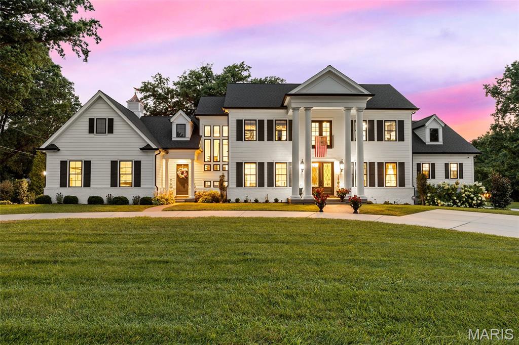 Set on just over an acre in Frontenac's coveted Radcliffe subdivision, this stately 4,724 square foot residence with a side-entry four-car garage and fully finished lower level sits within the acclaimed Ladue School District. The current owners took the original structure down to the ground and built entirely new in 2019, delivering the scale, systems, and finish level only true new construction can offer. A circular drive winds past mature trees and manicured gardens to a columned portico and covered front porch. Step through the double entry doors into a light-filled foyer crowned by a coffered ceiling and crystal chandelier, with 10 foot ceilings, 8 foot doors, and engineered hardwood flooring throughout the main level. The great room is a showpiece beneath a coffered ceiling, anchored by a striking black fireplace with custom mantel and a wall of black-framed windows overlooking the grounds. The kitchen is a chef's dream. An expansive center island with seating and prep sink sits beneath ornate pendant fixtures, surrounded by custom white shaker cabinetry, gold-toned hardware, and quartz countertops. Sub-Zero refrigeration and Wolf appliances anchor a fully integrated package with double ovens, induction and electric cooktops, range hood, microwave, and ice maker, and a walk-in pantry keeps everything within reach. Open to the kitchen, the hearth room is where everyone will gravitate. Soaring vaulted ceilings with exposed beams, a floor-to-ceiling stone fireplace flanked by custom built-ins, and walls of windows make it equal parts dramatic and comfortable. It is the ideal spot for morning coffee, casual dinners, and everything in between. The formal dining room sits at the front of the home with crown molding and a crystal chandelier, while a dedicated wet bar with dark cabinetry, undermount sink, and beverage refrigerator connects it to the kitchen, making entertaining effortless. A private main-floor primary suite occupies its own wing, featuring plush carpeting, a tray ceiling with crystal chandelier, an inset fireplace, and room for a seating area overlooking the backyard oasis. The spa-inspired primary bath is a genuine retreat with heated floors, a freestanding soaking tub beneath its own chandelier, an oversized glass-enclosed steam shower with marble bench, dual vanities, and two custom walk-in closets. Main level laundry is handled in style with a utility sink and custom cabinetry, and a mudroom off the garage with built-in lockers keeps the daily coming and going organized. Upstairs, a spacious second living room makes a natural landing spot for homework, movie nights, or simply giving everyone room to spread out. Three generously sized bedrooms, each with plush carpeting, a private ensuite, and a walk-in closet, provide an arrangement families and guests alike will appreciate. The finished lower level extends the living space dramatically. A recreation room with polished concrete floors offers dedicated zones for lounging, media, and a ping pong table, served by a custom wet bar with black cabinetry, mirrored backsplash detailing, built-in sink, and refrigeration. A carpeted office with egress window sits just off the main gathering area, finished with a built-in window bench and gold-toned chandelier, functioning equally well as a fifth bedroom or guest suite. A full bathroom, dedicated home gym, sauna, and extensive storage complete the level. The backyard oasis boasts a heated gunite pool with integrated steps, sun shelf, and patterned tile border, paired with a spa and stone-clad fire bowls for cool evenings. The oversized covered patio is finished like an interior room, with a coffered ceiling, shiplap detailing, dual ceiling fans, recessed lighting, a mounted television with integrated sound, and space for both full outdoor dining and lounge seating. All of this sits minutes from Plaza Frontenac, downtown Clayton, and Highway 40.