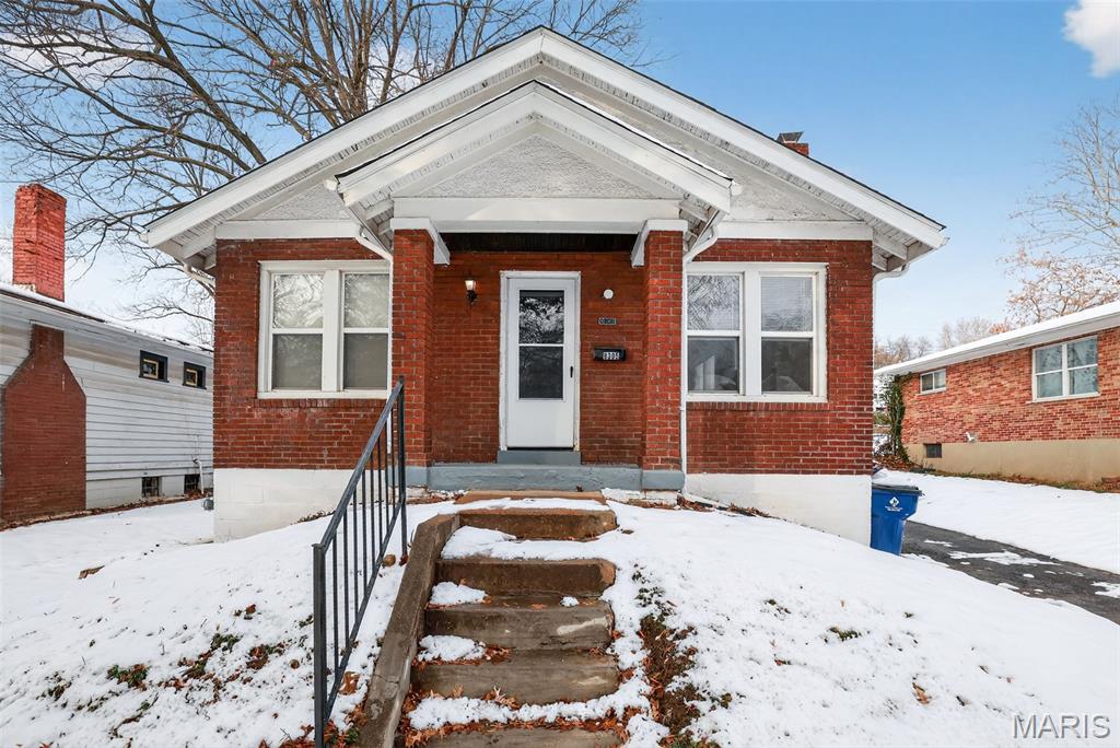 This charming brick bungalow offers a welcoming blend of character and updates, featuring a bright interior with neutral tones and gleaming hardwood floors throughout the main level. The spacious living room is highlighted by abundant natural light and a decorative fireplace, creating a warm focal point. The adjacent dining area flows into a well-equipped kitchen with stainless steel appliances, granite countertops, and ample cabinet space. Generously sized bedrooms provide comfort and versatility, while the updated bathroom includes a classic tile tub surround and modern vanity. A large, unfinished basement offers excellent storage or potential for future finishing. Outside, the home includes a detached garage, a partially fenced yard, and a cozy front porch perfect for relaxing. Set on a snow-covered lot with mature trees, this home blends charm, functionality, and opportunity.