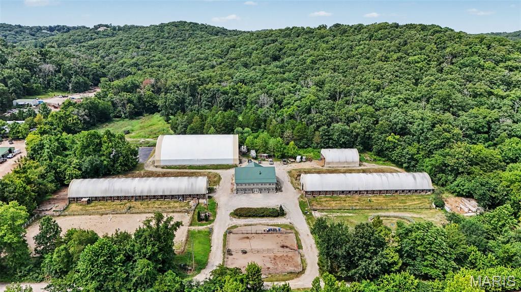 For decades, Castlewood Stables has been a familiar name in the area, offering a rare combination of location, land and remarkable infrastructure in the heart of St. Louis County. Established in 2006 and successfully operated as a boarding and training barn since its opening, the property is now ready for its next chapter.

Set on 10.53 acres, Castlewood Stables offers exceptional versatility for an equestrian operation, equipment and vehicle storage, workshops, recreation, gatherings or other pursuits requiring substantial indoor and outdoor space.

The equestrian facilities include a 32-stall barn with a tack room and two wash bays, along with a mirrored unfinished barn designed to accommodate up to 32 additional stalls, a tack room and wash bays. Currently used for equipment storage, the unfinished barn provides tremendous flexibility for future use. Additional improvements include a 40x60 hay and shavings barn, a lighted 100x140 indoor arena, a 100x200 outdoor arena and a 100x100 asphalt surface formerly used as a sport court and now providing substantial trailer parking.

While its equestrian legacy is undeniable, the scale and flexibility of this property open the door to possibilities far beyond horses. Whether continuing its established use, exploring the potential for a new business venture, creating expansive recreational or training space, hosting gatherings or bringing an entirely different vision to life, the existing buildings and infrastructure provide an exceptional starting point.

The 5,640-square-foot home offers 5 bedrooms, 4 full bathrooms and a flexible one-and-a-half-story layout. The main level features an open living area with high ceilings and a wood-burning fireplace, a spacious kitchen with custom cabinetry, granite countertops, a large island and walk-in pantry, a primary suite, two additional bedrooms and a dedicated office. The partially finished walkout lower level includes two bedrooms, two full bathrooms, a second kitchen, recreation space, laundry and abundant storage. The furnished walkout lower level, complete with two bedrooms, a full bathroom and a second kitchen, offers the potential for a separate apartment.

Generous indoor and outdoor entertaining areas provide space for personal gatherings, barn events and larger celebrations. The property adjoins wooded government land, creating a private and scenic backdrop that feels removed from it all while remaining conveniently located.

Continue the legacy of Castlewood Stables or reimagine this one-of-a-kind property for your own vision. An adjoining 20-acre parcel may also be purchased separately for additional privacy, recreation or expansion.