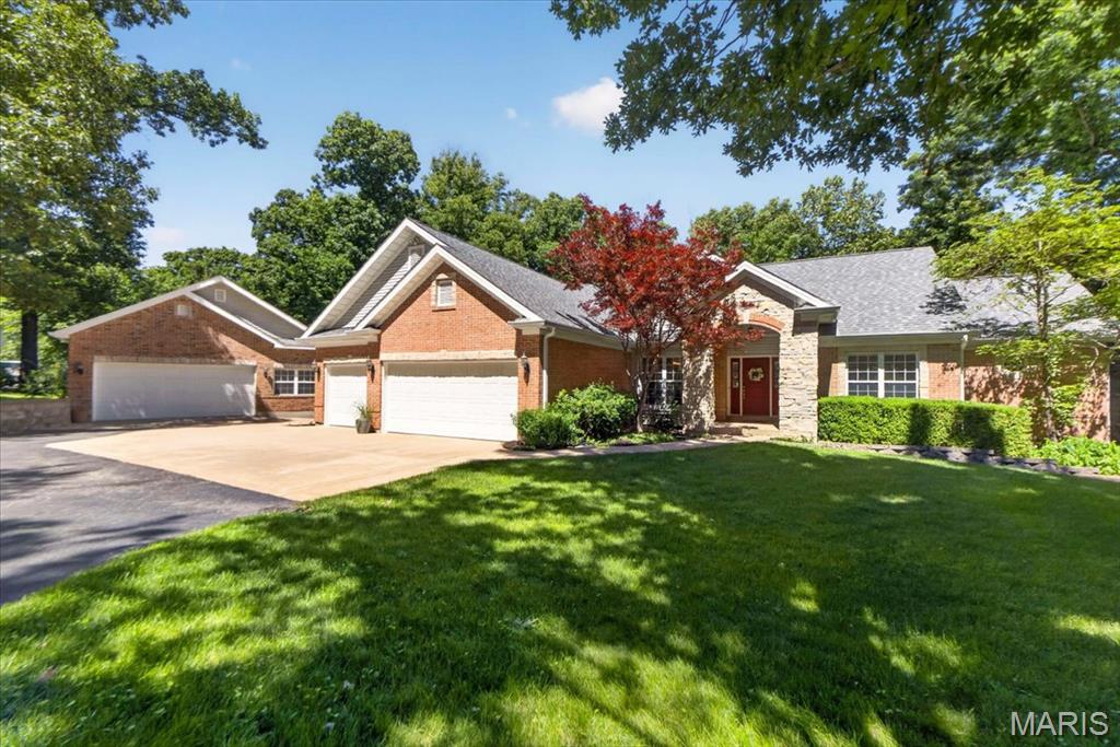 Set on 3.05 private wooded acres, this custom atrium ranch lands in the sweet spot between the St. Louis and St. Charles corridors and Missouri wine country, an easy drive either direction. Inside and out, it offers what buyers rarely find: room to spread out, work, and entertain without compromise. The garage space here is genuinely rare. An attached oversized 3-car handles everyday vehicles with direct access to the home, and a separate detached oversized 2-car adds a dedicated workshop. That is five-plus garage parking spaces total, plus a true work area for projects, equipment, and storage, with no HOA. Inside, hardwood floors run throughout the main level beneath vaulted and coffered ceilings, custom millwork, and arched openings. The great room opens up with a wall of windows facing the woods, a gas fireplace, and an open staircase to the lower level. The kitchen has light wood cabinetry, granite counters, a custom tile backsplash, stainless appliances, a center island, and a pantry. A bay-windowed breakfast area opens to the deck in back. A separate formal dining room handles the holidays. Main-floor living anchors the home with a private primary suite featuring a coffered ceiling, crown molding, a walkout to the deck, and a luxury bath with dual vanities, a jetted tub, and a separate shower. A second main-level bedroom, a full bath, and a convenient main-floor laundry round out single-level ease. The deep-pour walkout lower level lives like a second home. A family room with a striking floor-to-ceiling gas stone fireplace, a rec area with space for the pool table, a full wet bar with wine cooler, a dedicated exercise room, two additional bedrooms, and a full bath all open to the trees through a private walkout, ideal for guests, extended family, or weekend entertaining. Outside, the lifestyle continues across an expansive multi-level deck, a screened porch, and a shaded under-deck patio, all overlooking a level, usable lawn wrapped in mature woods. Pre-wired for speakers throughout. Zoned for sought-after Francis Howell schools and Daniel Boone Elementary, minutes from the Katy Trail, Augusta, and the wineries, with an easy commute to the St. Charles and Chesterfield corridors. Privacy, space, and main-floor living, all on a rare wooded acreage. NEW ROOF (2025) This is the one you have been waiting for, schedule your tour today.