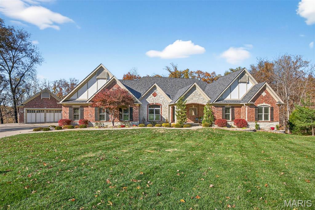 Welcome to 707 Crown Pointe Farms, a premier estate in the heart of Defiance. Privately situated on a cul-de-sac within the Francis Howell School District, this custom-built ranch rests on 4.3 acres and offers nearly 6,200 square feet of finished living space. The main level showcases a soaring great room with vaulted ceilings, a floor-to-ceiling stone woodburning fireplace, built-in shelving, and large windows overlooking the wooded backyard. The expansive kitchen features granite countertops, upgraded stainless steel appliances, a breakfast room, and a connecting hearth room with its own masonry gas fireplace—both overlooking scenic wooded views. A formal dining room sits just off the kitchen, providing the perfect setting for gatherings and special occasions. The home offers five bedrooms and four full bathrooms, including a primary suite with a large walk-in closet and a spa-inspired bath with a jetted tub and walk-in shower with dual shower heads. Designed for convenience, the main level includes a mudroom with laundry and a full bathroom, seamlessly connected to a den/office area with its own garage access and private driveway entry. The walkout lower level, built with a 9’ pour, features a full bar, media and recreation areas, a stone gas fireplace, a home gym, a charming craft room, and a moody bathroom. The outdoor space is equally impressive, with two patio areas overlooking the private acreage, beautiful landscaping, stunning eave lighting across the front of the home, dusk-to-dawn carriage lighting, and an irrigation system. Completing the property are a 2-car attached garage, oversized 2-car detached garage, and a new architectural roof (2024). 707 Crown Pointe Farms delivers refined living, exceptional craftsmanship, and the privacy of a true Defiance retreat.