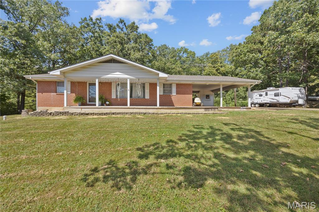 Charming full-brick home situated on a spacious corner lot in the quiet Bust Subdivision, offering peaceful living just minutes from town, schools, and the city park! Step inside to warm hardwood floors and a cozy fireplace in the inviting living room. This well-maintained residence features 3 bedrooms and 1 full bath, plus 2 convenient half baths—one in the master bedroom and another in the basement. The full, partially finished basement provides excellent flexibility for a recreation room, workshop, or extra storage. Outside, you'll love the huge concrete driveway with ample room to park a camper or RV, leading to a 2-car carport. Enjoy relaxing or entertaining on the large back concrete patio overlooking a great, level yard. A solid brick classic with fantastic potential and space for all your vehicles and outdoor gear!