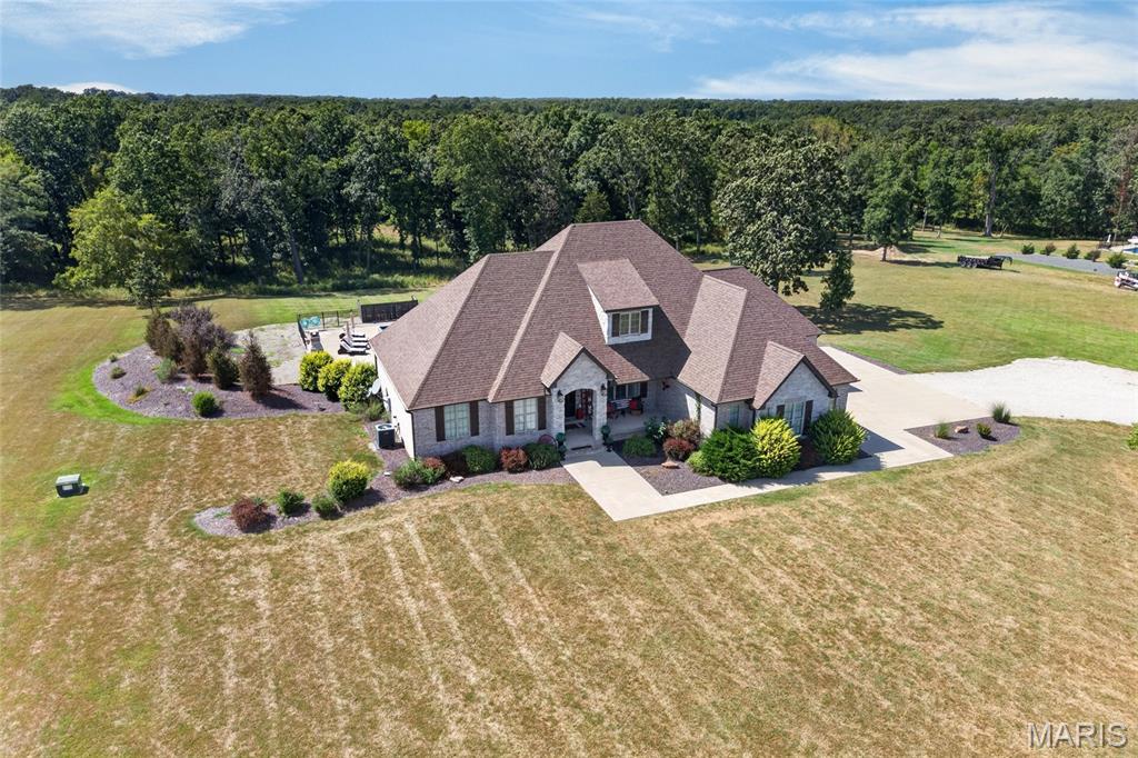 Welcome to this beautifully designed, immaculate 5-bedroom, 3.5-bath home situated on 5 acres just 5 minutes outside the city limits. Thoughtfully designed with quality finishes and attention to detail throughout, this move-in-ready home offers both functionality and style. From the front door, an attractive arched opening welcomes you into the living area, while the entry from the garage provides a convenient and beautifully finished transition into the home. Each room offers its own thoughtfully designed details, creating a cohesive and warm atmosphere throughout. The kitchen is a true standout, featuring custom white cabinetry, a gorgeous, stained island that beautifully complements the hardwood flooring, marble countertops, and ample workspace. The living room is filled with natural light and features a stunning brick/stone fireplace accented by beautiful wood beams. The finished basement provides exceptional additional living space, including another living room, kitchen area, 2 guest bedrooms, full bath and a huge storage area. The basement also connects to the John Deere garage, for additional storage. This home offers the much-desired open concept and split bedrooms. Throughout the home, you’ll find carefully selected architectural details, including wood-accent walls, painted accent walls, and distinctive archways, granite countertops in all bathrooms, abundance of windows, and central vacuum system that adds everyday convenience. Outside, the 5-acre property offers privacy and plenty of room to enjoy the outdoors. Relax on the covered porch or deck or gather around the impressive in-ground pool surrounded by an abundance of concrete space for seating, lounging, and entertaining. With its custom finishes, natural light, thoughtful design, spacious living areas, incredible outdoor amenities, and convenient location just minutes from the city, this meticulously maintained property is truly a must-see!