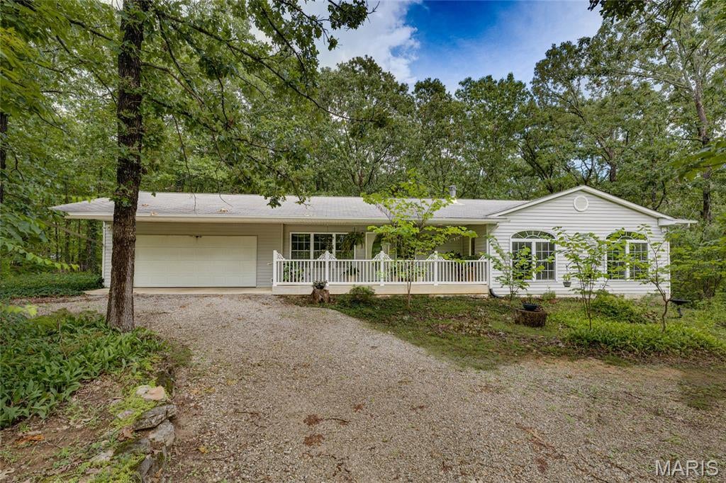 Peaceful Country Living with Modern Convenience on 3 Wooded Acres, where privacy, comfort, and functionality come together in a beautiful, wooded setting. Nestled in a small, peaceful neighborhood, you'll enjoy the tranquility of country living while being just minutes from shopping, restaurants, schools, and everyday conveniences, the best of both worlds.

A charming covered front porch welcomes you home and provides the perfect place to relax and enjoy the peaceful surroundings. Inside, you'll love the open-concept family and dining area, creating a warm and inviting space for entertaining or spending time with family. The home features 36-inch interior doors throughout, offering both accessibility and a spacious feel.

The primary suite is a private retreat designed for both comfort and accessibility, featuring an atrium door that opens to your own private deck, the perfect place to enjoy peaceful mornings surrounded by nature. A spacious, wheelchair-accessible walk-in closet and wheelchair-accessible en-suite bath provide convenience and ease of living. Just across the hall, a charming secondary bedroom showcases custom built-in cabinetry for hobbies, quilting, sewing, crafts, or a stylish home office, while a beautiful built-in stained glass window fills the room with colorful natural light and timeless character, making it one of the home's most memorable spaces.

The unfinished basement offers endless opportunities to expand your living space, create the workshop of your dreams, or simply enjoy abundant storage. A cozy wood-burning stove adds warmth and rustic charm for cooler months, and as an added bonus, the seller is including approximately one year's supply of seasoned firewood, so you'll be ready to enjoy it from day one.

Outside, the 3 acre wooded lot provides exceptional privacy, room to roam, and abundant wildlife. Pet lovers will appreciate the dedicated dog run, while the convenient garage entrance makes everyday living even easier.

If you've been dreaming of a home that offers the serenity of country living without sacrificing the convenience of town, this property delivers. Enjoy peaceful mornings, quiet evenings, and plenty of space to spread out, all while being only a short drive from the shopping, dining, and amenities you use every day.