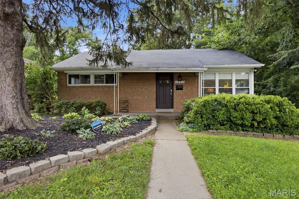 Tucked away on a quiet private street in the highly sought-after Webster Groves School District, this charming brick ranch offers the perfect blend of timeless character and everyday comfort. Enjoy inviting curb appeal with a welcoming covered front porch and a peaceful setting you'll love coming home to. Conveniently located within walking distance to the elementary school, this home offers an ideal combination of location and lifestyle.  Natural light fills the interior, highlighting the hardwood floors throughout the main level and six-panel doors. The spacious living room flows seamlessly into the dining room, creating an inviting space for both everyday living and entertaining while overlooking the backyard.  The updated kitchen features custom cabinetry, granite countertops, ceramic tile flooring, and black and stainless steel appliances. The main-level bathroom offers a granite-topped vanity and ceramic tile tub/shower surround. Two generously sized bedrooms complete the main level.  The walk-out lower level provides exceptional additional living space with a comfortable family room, third bedroom featuring an egress window and walk-in closet, second full bathroom with dual-sink vanity and step-in shower, and a large storage room offering plenty of space for organization.  Step outside to enjoy the private, fenced backyard featuring a patio—perfect for relaxing, entertaining, or enjoying your morning coffee. The adjacent vacant lot, professionally maintained by its owner, provides an added sense of openness and privacy.  With its desirable Webster Groves location, flexible living space, and charming features throughout, this home is ready for its next owner to make it their own.