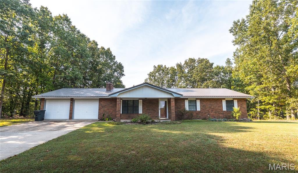 Welcome home to this well-maintained 3-bedroom, 2-bathroom home in St. Robert, Missouri, where a peaceful neighborhood setting meets everyday convenience. Situated on a spacious 1-acre lot and featuring a new metal roof installed in 2025, this property offers plenty of room to spread out while keeping you just minutes from the Fort Leonard Wood Main Gate, shopping, dining, and local amenities.

Step inside to a comfortable, inviting layout featuring laminate flooring throughout and ceramic tile in the kitchen for easy maintenance. The living room is the perfect place to unwind, with a wood-burning fireplace creating a warm and welcoming focal point for cozy evenings at home.

The kitchen provides a functional space for preparing meals and gathering with family or friends, while three bedrooms and two bathrooms offer flexibility for everyday living, guests, or a home office.

Start your mornings with coffee on the covered front porch while enjoying the quiet surroundings. The large lot provides plenty of outdoor space for entertaining, gardening, pets, or simply enjoying a little extra privacy.

An oversized garage adds even more versatility, offering ample room for vehicles, storage, and the potential for a dedicated workshop or hobby area.

With its 2025 metal roof, generous acreage, convenient St. Robert location, and comfortable features, this home offers a wonderful balance of space and accessibility. Schedule your private showing today and see all this property has to offer!