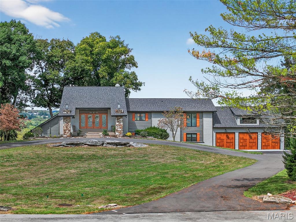 Discover a one-of-a-kind retreat on 3 private acres extending to the riverfront, offering breathtaking views of the Meramec River and George Winter Lake. With over 4,000 sq. ft. of total living space, this residence seamlessly blends modern luxury with a serene, natural setting. Designed for both everyday living and perfect for hosting and gathering, the home features 4 spacious bedrooms, 3.5 bathrooms, and a bonus space above the garage awaiting your finishing touches. Indoors, an open-concept floorplan highlights soaring ceilings, warm wood accents, and a dramatic stone fireplace. The gourmet kitchen is the heart of the home with custom cabinetry, a large quartz center island and countertops, and designer stainless appliances. The primary suite is a true sanctuary, boasting a spa-inspired bathroom with a steam shower, a soaking tub and a custom walk-in closet suite. The light filled lower level boasts multiple living spaces, a full bar, 3 bedrooms, 2 stunning bathrooms and a custom laundry room that opens to the oversized 3 car, extra deep garage with full height loft ready to be finished. Both an indoor and outdoor bar elevate the home’s entertainment potential, making it the ultimate destination for hosting. Multiple levels of decks, a covered veranda, extensive hardscaping, and plenty of usable yard space create endless opportunities for gathering and outdoor enjoyment. Resort-style amenities include an infinity-edge pool, cozy firepit, and expansive lounge areas—all designed to showcase the stunning river and lake views. Whether entertaining a crowd or savoring peaceful solitude, this property offers a rare balance of refined elegance and natural beauty.