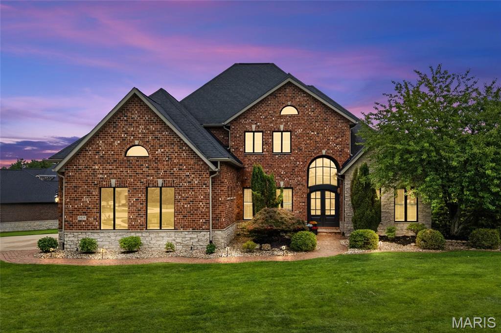 There is nothing like this all-brick and stone luxury home in Edwardsville’s exclusive Stone Cliff Manor neighborhood. Arched double wood front doors set the stage for a dramatic main level defined by hardwood floors, soaring ceilings, and spaces designed for everyday living and special entertaining. The two-story great room anchors the home with its wall of windows and floor-to-ceiling stone fireplace. A formal dining room framed with archways under a tray ceiling and new chandelier sits nearby, and the renovated designer kitchen impresses with newly-painted custom cabinetry, high-end appliances, wine cooler, new custom granite countertops, new backsplash, large center island, walk-in pantry, new lighting, and a breakfast room with vaulted ceiling and expansive views. An executive office with French doors and crown molding lends itself to focus, while the primary suite provides sanctuary with its vaulted ceiling, bay window sitting area, two walk-in closets, and spa-like bath with dual vanities, a custom-tiled walk-in shower, jetted tub, and water closet. Upstairs, three generously sized bedrooms each offer a walk-in closet and private bath access, two of which feature Jack-and-Jill access. The walkout lower level is its own destination: 12-foot ceilings, expansive wet bar, billiard area, family room, and two finished bonus rooms perfectly suited as a gym, media room, game room, or storage. The lower-level fifth bedroom with library/sitting area and walk-in closet functions beautifully as a guest suite or second primary. Outside, a spacious deck and covered paver patio with recently expanded patio area overlook a large corner lot with sweeping tree-lined views. Dual HVAC units new in 2023, and fresh paint and upper-level carpet in 2026. Stone Cliff Manor is an upscale neighborhood with scenic pond, community pavilion, and impeccably kept spaces located within the Edwardsville School District with convenient Interstate access, situating you just thirty minutes from The Gateway Arch and St. Louis Lambert International Airport. All this with Edwardsville’s outstanding shopping, dining, and recreational opportunities. Inquire for more information on this beautiful home or to schedule your private tour of this unparalleled luxury home.