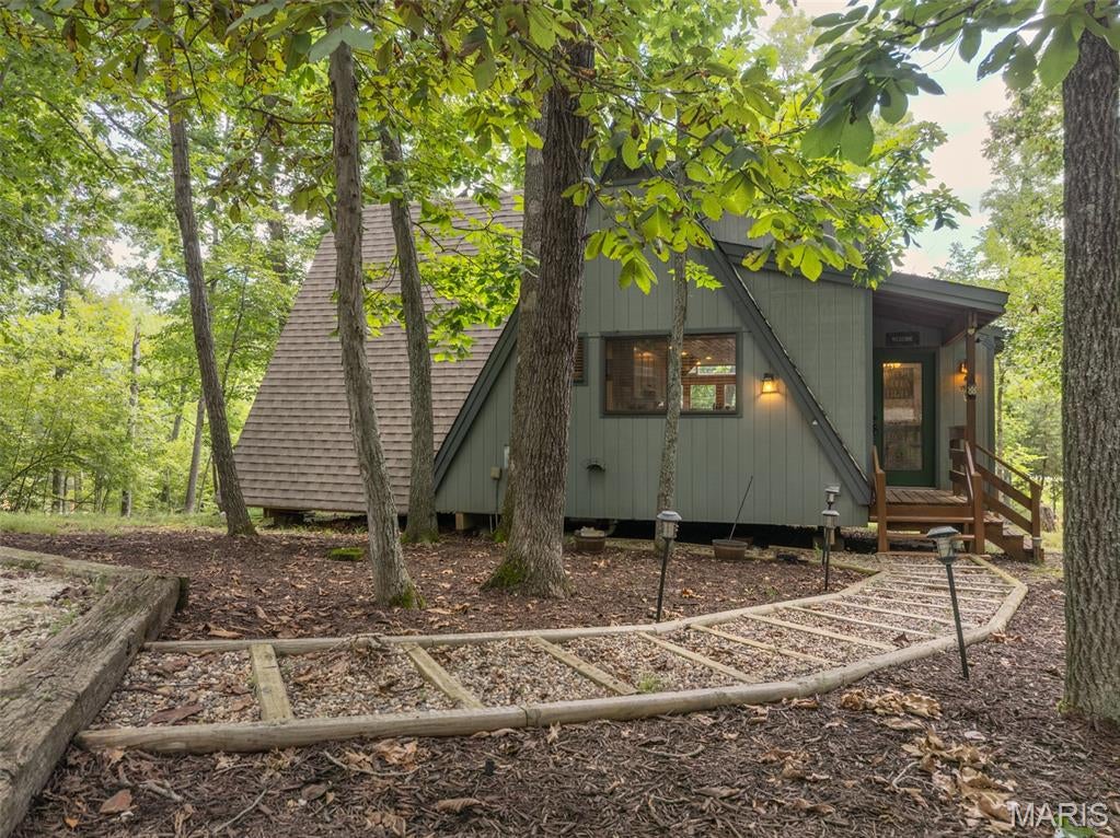 Gorgeous A-Frame chalet on Trophy Lake, offering a rare combination of privacy, charm, and lakefront living just minutes from Innsbrook's front gate and Championship Golf Course. Set on 1.57 park-like, tree-canopied acres with a gentle slope to the water's edge, this home delivers the peaceful, tucked-away feel Innsbrook owners look for without sacrificing convenience. Inside, walls of double-pane windows flood the expanded great room with natural light and frame beautiful views through the surrounding hardwoods. A full masonry wood-burning fireplace anchors the space, while the remodeled kitchen, custom cabinetry, and breakfast bar make everyday living and entertaining effortless. Hardwood floors, vaulted ceilings, and special millwork add character throughout, and a spacious separate dining area gives room to gather. Two large bedrooms plus an expanded sleeping loft comfortably sleep a crowd, and the main level bathroom has been newly renovated for a fresh, updated feel. Step outside to a sprawling deck, recently power-washed and freshly stained, perfect for morning coffee or evening entertaining above the water. Down at the shoreline, the beach area has been freshly spruced up with a layer pea gravel, creating an inviting spot to swim, launch a kayak, or just relax by the private dock. The driveway has also been freshly graded, adding to the home's move-in-ready appeal. This chalet comes mostly furnished, making it a seamless transition for a vacation home or income-producing property, and offering an excellent opportunity for investors looking to tap into Innsbrook's proven short-term rental market. With its blend of lakefront serenity, recent updates, and private 1.57-acre setting, 927 Trophy Woods is a special find within the gates of Innsbrook!