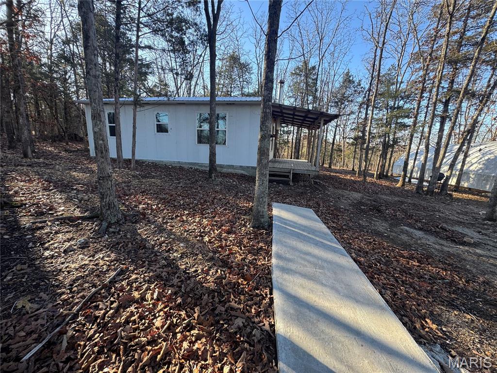 If you are looking for acreage with existing improvements and a private setting, this 15.56-acre property offers a variety of possibilities. A long private drive leads to a cabin situated among mature trees, providing a secluded location with room to explore and enjoy the outdoors.
The cabin includes two areas currently used by the owners for sleeping, a bathroom with plumbing, a kitchen area, living space, covered front porch, and a metal roof. The property has previously been used as a homestead and includes a well, pond, and electricity already in place. Additional improvements include two large hoop buildings (negotiable), along with an established strawberry patch. The combination of open areas and wooded acreage provides opportunities for a variety of recreational and agricultural uses.Whether you're looking for a recreational property, a weekend retreat, a future homesite, or acreage for hobby farming or homesteading, this property offers existing infrastructure and a private setting to accommodate a variety of needs. Buyers are encouraged to verify all information important to their intended use of the property.