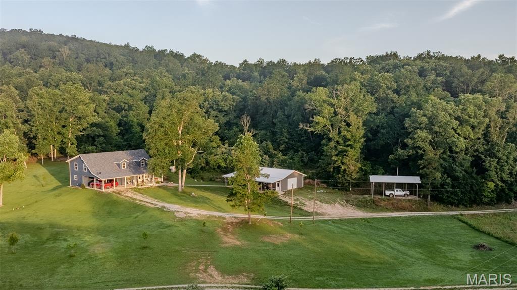 Presenting a turn-key residential and recreational opportunity in Reynolds County, Missouri, this 5+/- acre property features a meticulously crafted custom home completed in 2022.  Designed for modern comfort and efficiency within a beautiful country setting, this property offers a seamless blend of sophisticated living and practical outdoor utility, ideal for those seeking a primary residence or a well-appointed rural retreat.

The residence itself spans 2645 square feet, offering 3 bedrooms and 2.5 bathrooms. Quality construction is evident throughout, highlighted by a geothermal system for efficient climate control and a backup generator for uninterrupted power. Inside, the home boasts a primary suite for private comfort, a generous walk-in pantry, and a distinctive loft overlooking the main living space, accented by rich wood ceilings. A partial basement provides additional functional space.

Beyond the main dwelling, the property includes substantial improvements tailored for hobbies and storage. A 30x50 workshop/garage provides ample space for projects, equipment, or vehicles. Additionally, dedicated camper/RV storage with both electric and water hookups offers convenience for recreational vehicle owners. The 5+/- acres present level to gently rolling topography, well-suited for various outdoor pursuits, while available electric, water, and septic utilities ensure full functionality. Access is provided via a well-maintained gravel road, maintaining rural charm without compromising accessibility.
