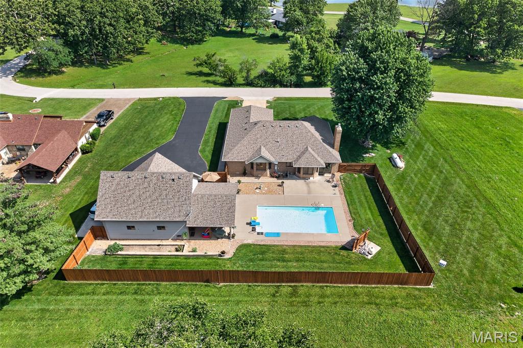 Nestled in a quiet country subdivision on the north side of town, this all-brick home strikes a balance between elegance and pristine care, offering a picturesque setting that will capture your heart from the moment you arrive. Imagine waking up to a serene lake, enjoying the views, stepping out for a morning stroll along winding trails, or casting a line to fish in the sparkling community lake—yes, fishing rights are yours! The neighborhood itself is a haven, boasting many acres of grounds and a scenic lake, inviting residents to embrace nature at every turn.  INSIDE the home, it seamlessly blends comfort and sophistication. The living and dining areas are thoughtfully enhanced by exquisite hardwood floors, Hickory Carmel Honey, & home is meticulously maintained. Three bedrooms and two and a half baths (one of the bedrooms has a wardrobe, all on one convenient level; the layout is both functional and inviting. With special features abound (a list of extras available), including an attached garage, large storm (6 people) shelter, PLUS A SHOP/ two-car garage with a spacious upper-level BONUS ROOM that could easily transform into a guest suite, creative studio, or even a caveman retreat—let your imagination roam! ENJOY and step outside into your own backyard oasis, where an IN-GROUND POOL awaits alongside a stunning OUTDOOR KITCHEN complete with a gas grill, a 2XL Big Green Egg, a sink with a disposal, and a cozy gas fireplace. Whether you're hosting lively gatherings or enjoying a quiet evening under the stars, this space is designed for memories. Lovely yards, both the front and back yards, a raised garden bed, and a cedar privacy fence that creates a retreat of relaxation. This home and its vibrant community invite you to experience a lifestyle where every day feels inspired. You’ll truly fall in love with the house & also with the welcoming neighborhood that surrounds it.