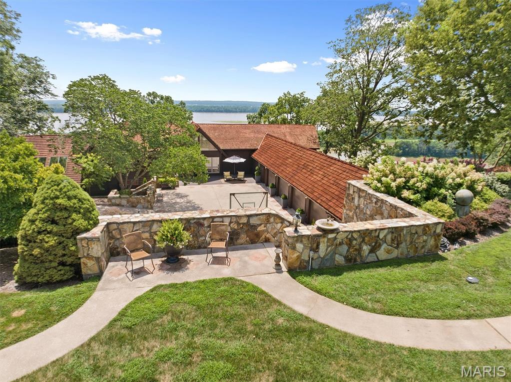 Your Mississippi River promontory estate delivers unmatched views and luxury living from its coveted limestone bluff placement, centrally located in the US,  plus along a National Scenic Byway. This 6,000 sq/ft lodge-style home sits beside a protected nature preserve, offering both privacy and convenience—just 40 minutes from an international airport and near major city amenities. Built for everyday comfort and large-scale entertaining, it features a soaring 2-story hearth, pub room opening to an expansive deck off the heated in-ground pool and an oversized primary suite with private sitting room having direct access to the full-length upper deck. Rich hardwood floors, exposed ceiling beams, and two well-placed wet bars within gathering areas add warmth and functionality. A walk-out basement with river views is ready for your gym, recreation space, or studio, while a 5-car garage and oversized courtyard provide space for vehicles, basketball, and more. Whether you’re enjoying mornings on the screened in porch over panoramic water views, hosting poolside gatherings, or relaxing in your private oasis, this home delivers the rare combination of scenic beauty, generous square footage, and refined design that makes it a true gem worth adding to your real estate portfolio.  Before making an offer on any property, buyer should independently verify all MLS data derived from various sources and not warranted accurate.