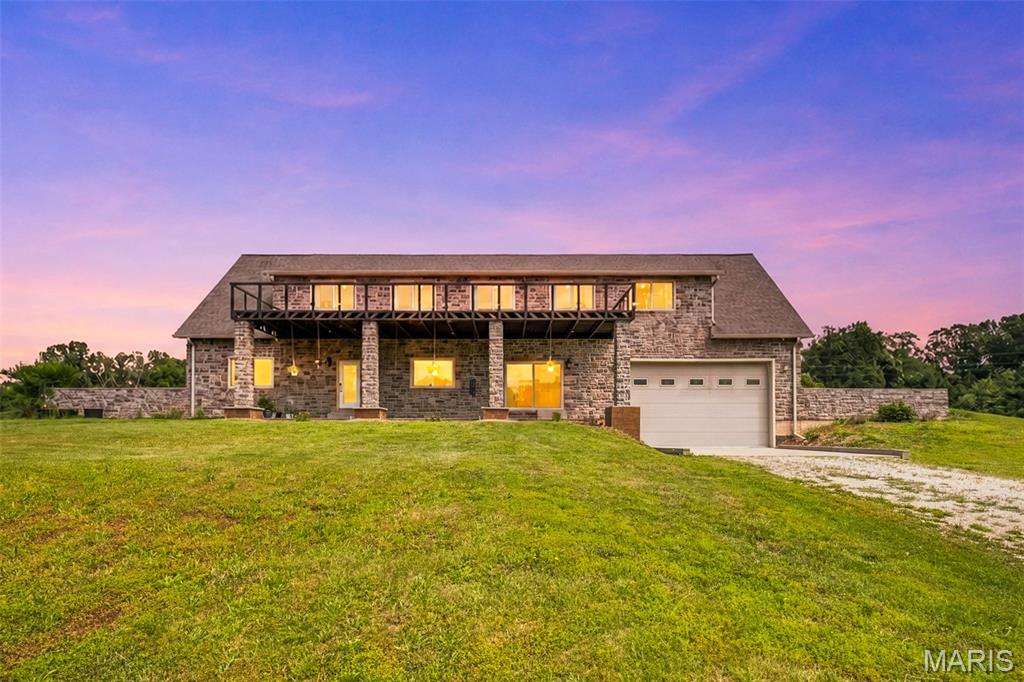 Tucked away on 3 private acres at the end of a quiet road, this stunning stone hillside home offers the perfect blend of comfort, efficiency, and recreation. Designed with energy savings in mind, the home's unique earth-sheltered construction provides remarkable natural temperature regulation, helping maintain a comfortable climate year-round with minimal heating and cooling needs. The front exterior walls are over 14 inches thick and feature extensive insulation combined with beautiful stone and masonry construction, creating exceptional durability, efficiency, and timeless curb appeal. Inside, you'll find a spacious open-concept floor plan with soaring ceilings, abundant natural light, and beautiful hardwood flooring throughout. The kitchen, dining, and living areas flow seamlessly together, creating an inviting space for everyday living and entertaining. With 3 bedrooms and 3 bathrooms, there is plenty of room for family and guests alike. The upgraded bathrooms offer a luxurious retreat, featuring elevated tile finishes, relaxing soaking tubs, and separate glass-enclosed showers designed for both comfort and style. Step outside to enjoy the stunning patio and upper-level deck overlooking the peaceful countryside. Whether you're enjoying your morning coffee, hosting friends, or simply taking in the views, the outdoor living spaces are sure to impress. The oversized garage provides ample room for vehicles, hobbies, and storage, with enough space to accommodate a boat, camper, or recreational equipment—perfect for taking advantage of nearby Mark Twain Lake and all the outdoor adventures the area has to offer. Additional conveniences include public water, private septic, and the potential for an off-grid lifestyle with minimal modifications. Offering privacy, efficiency, quality craftsmanship, and a setting that is hard to find, this one-of-a-kind property combines modern comfort with the peace and independence of country living. If you've been searching for a home that is as practical as it is beautiful, this exceptional stone retreat deserves your attention.